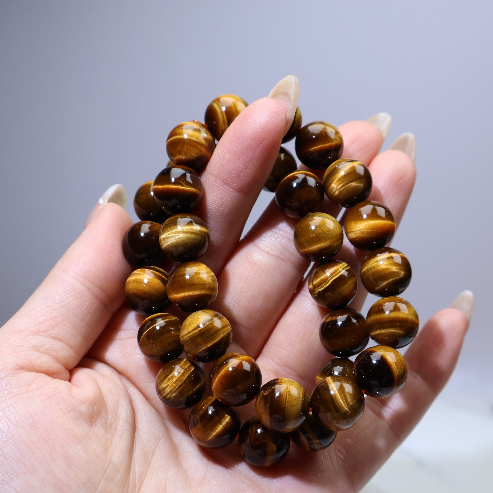 Handheld view of two Tiger’s Eye bracelets stacked together