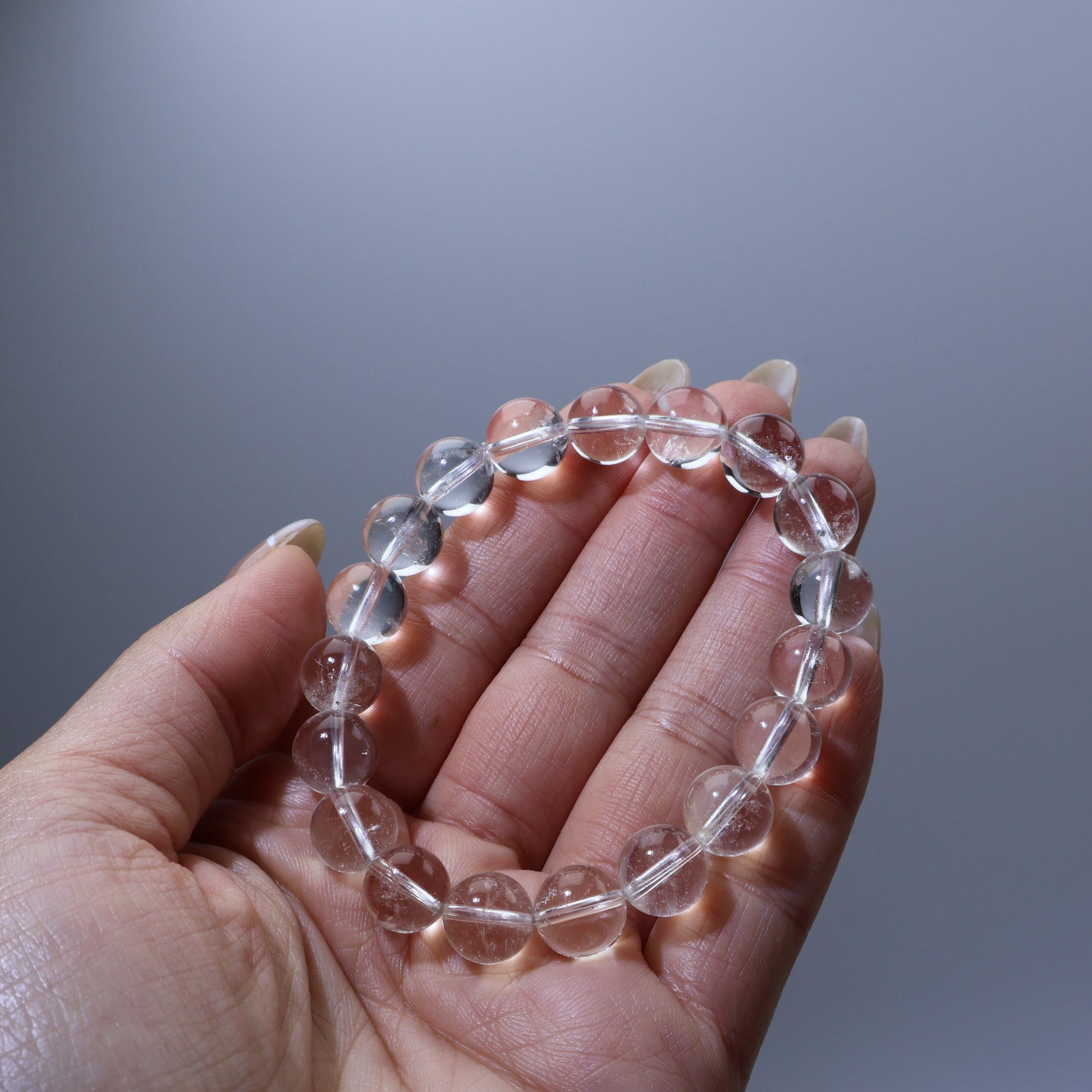 Hand holding transparent quartz bracelet – everyday energy stone