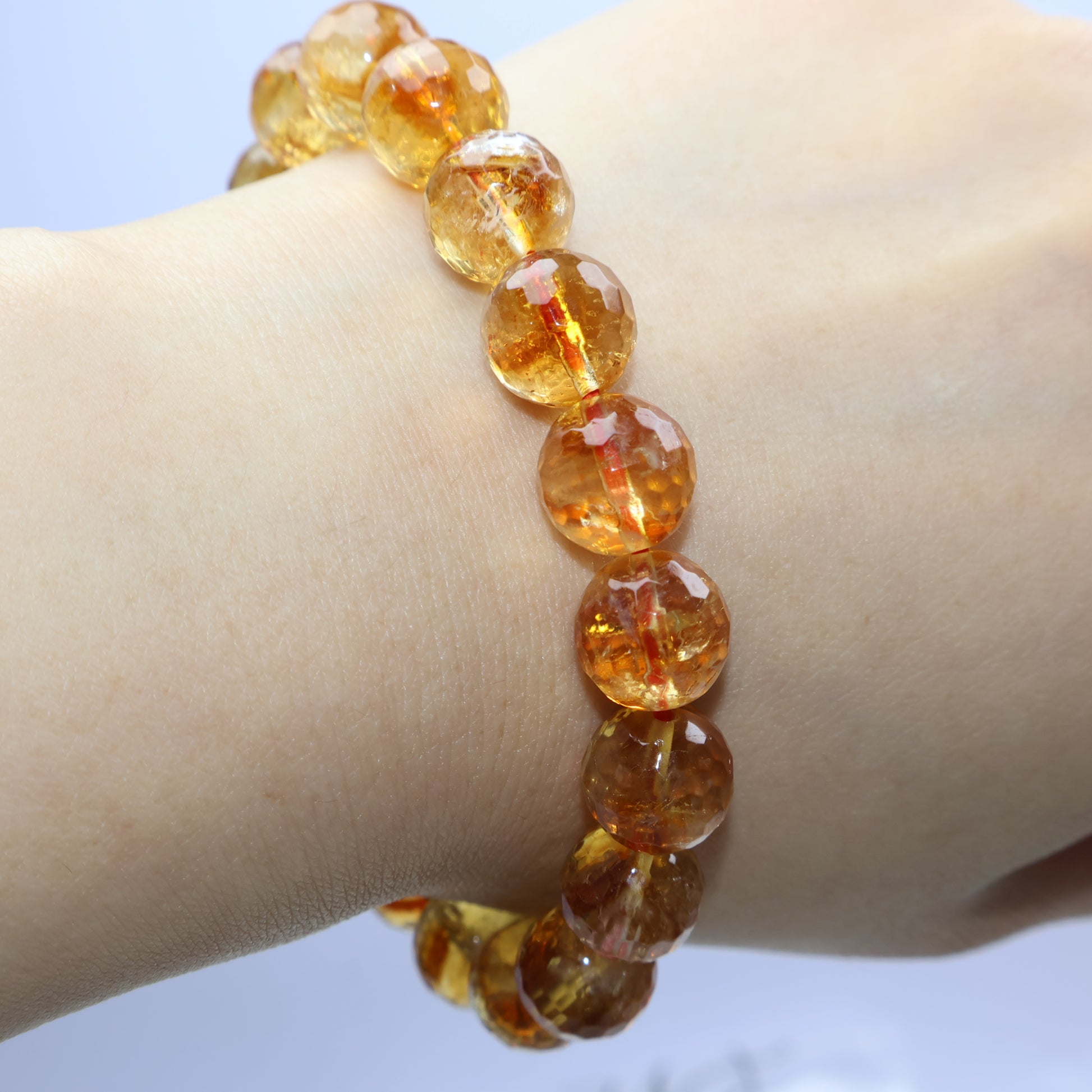 Top view of citrine bracelet on wrist, faceted surface reflecting soft light