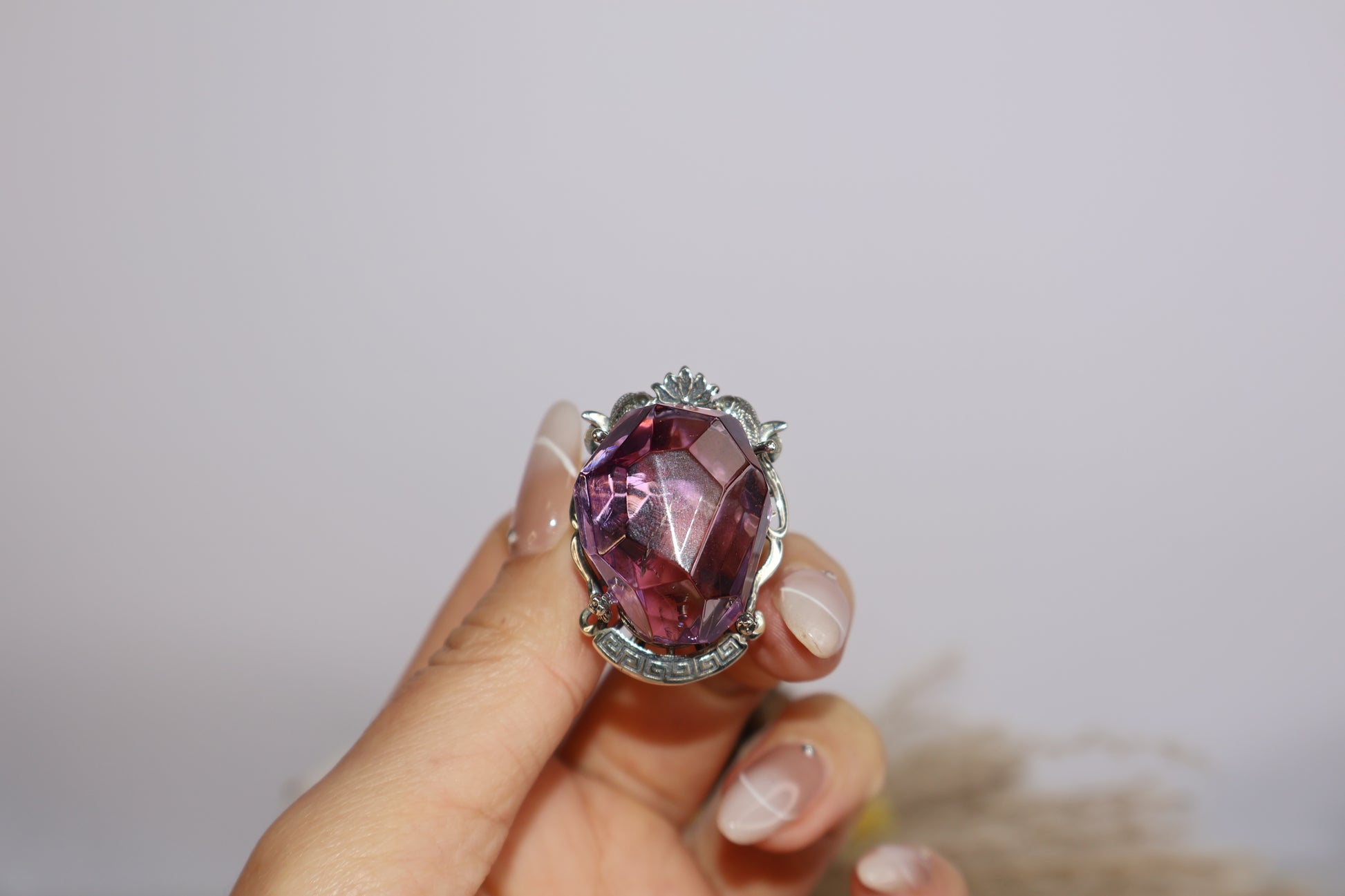 Front handheld close-up of double-fish ametrine ring with floral centerpiece