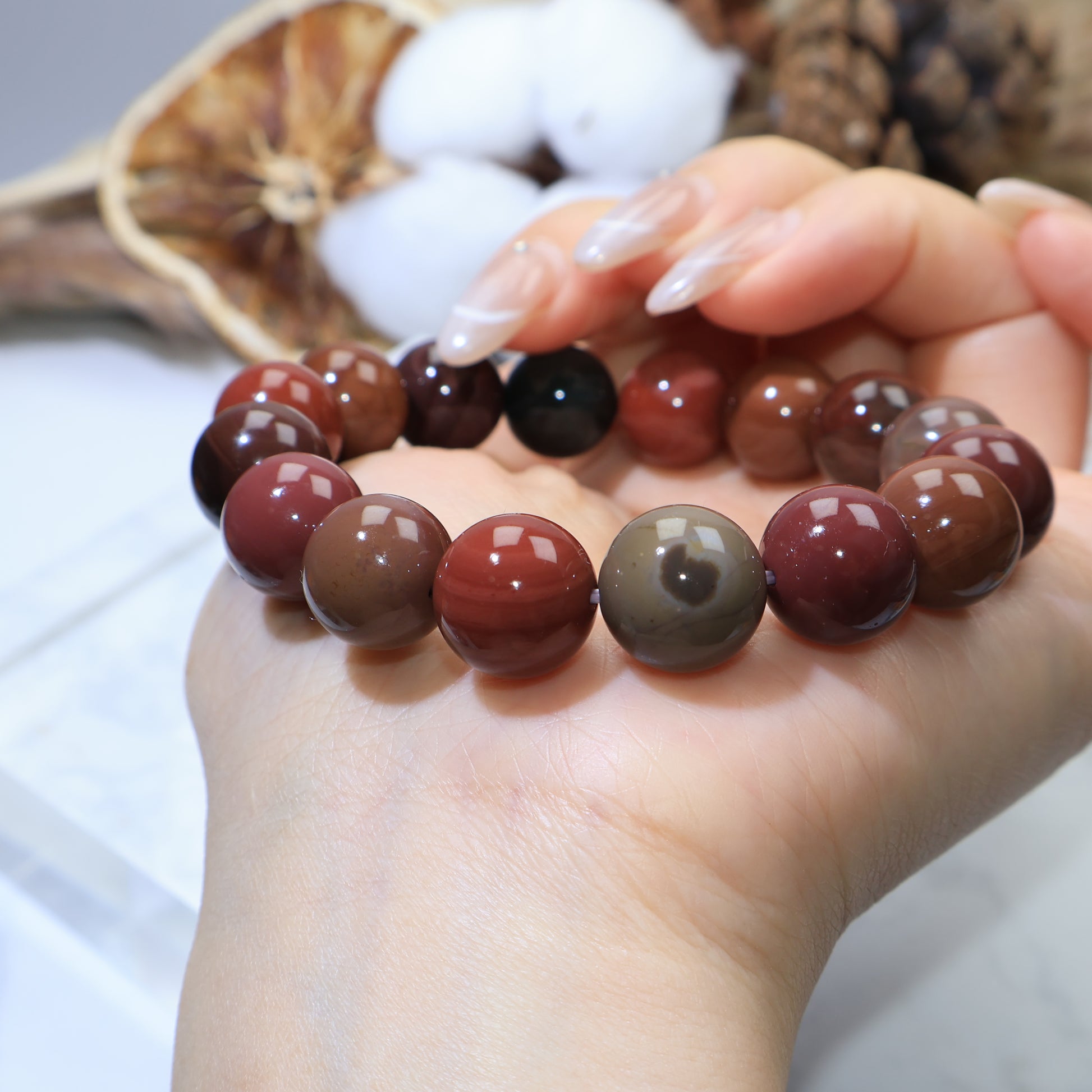 Hand-turned angle displaying mix of red, brown, and olive beads on wrist
