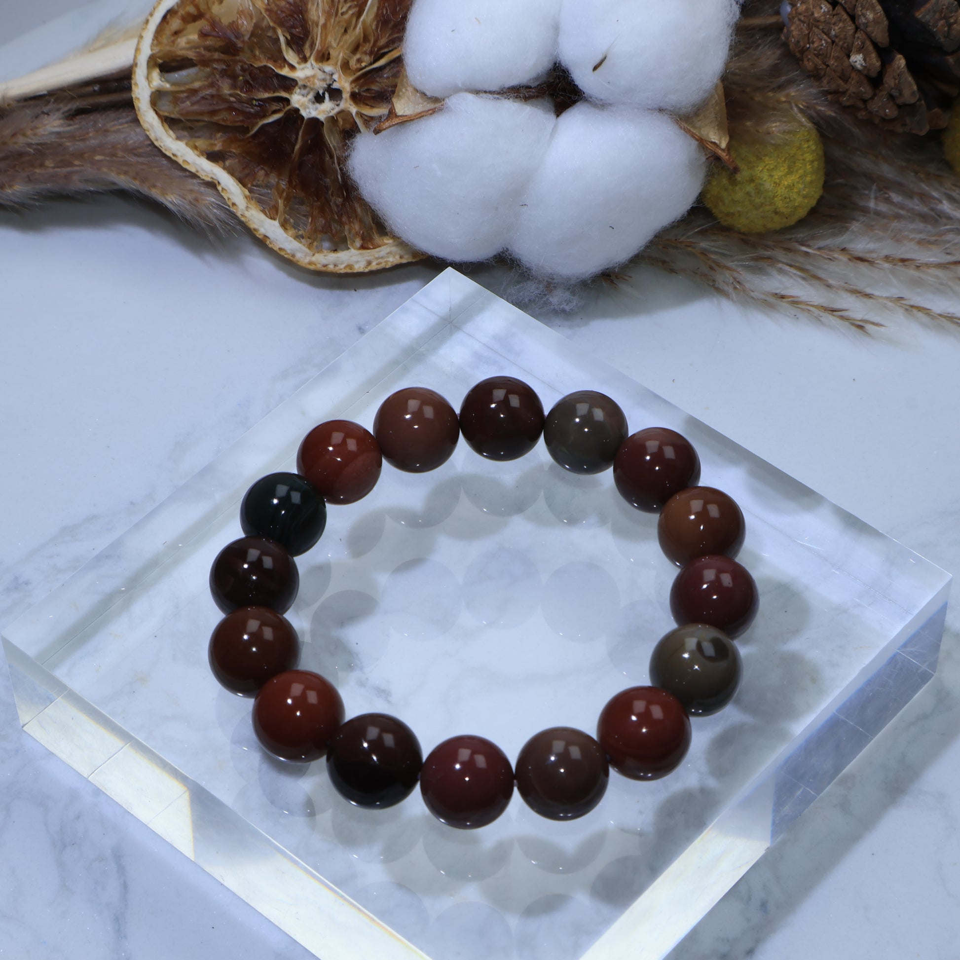 Top view of Alxa Agate bracelet on clear acrylic display, showing mix of earthy colors