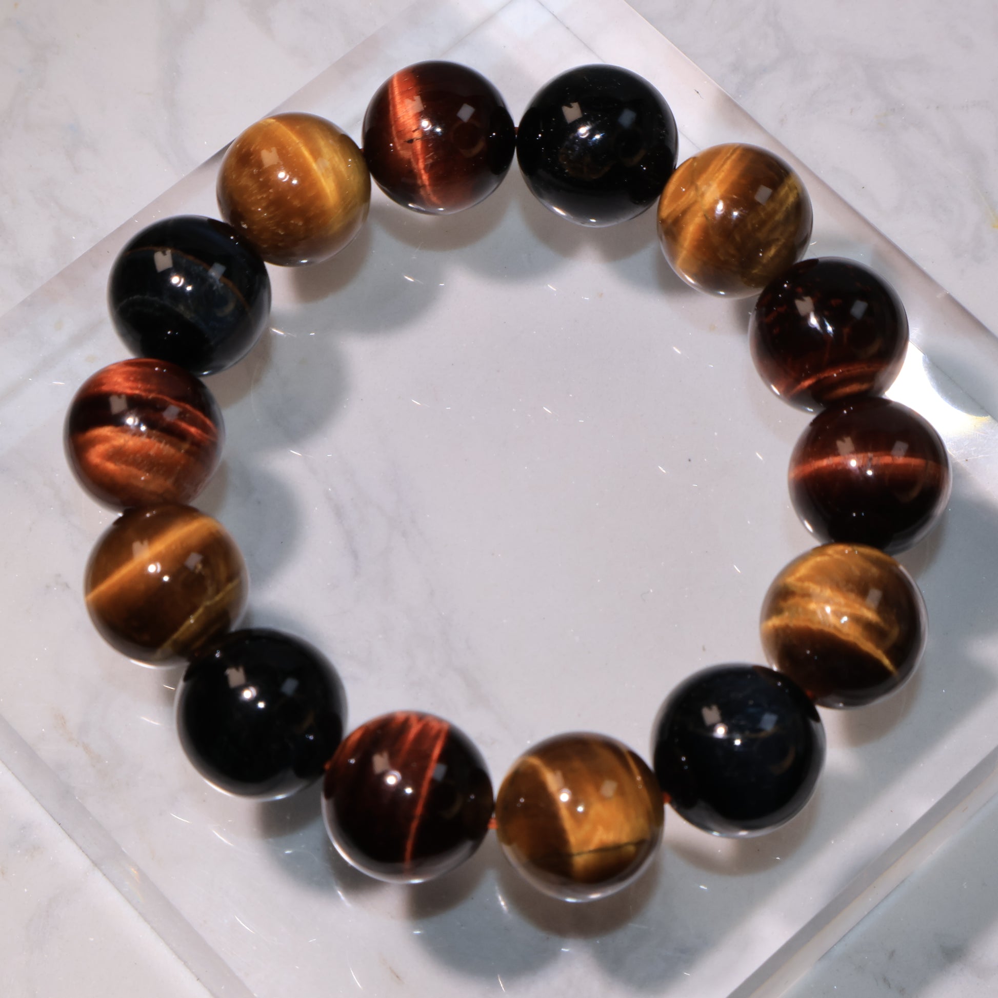 Triple Tiger Eye bracelet in golden, red, and blue colors displayed on marble surface.