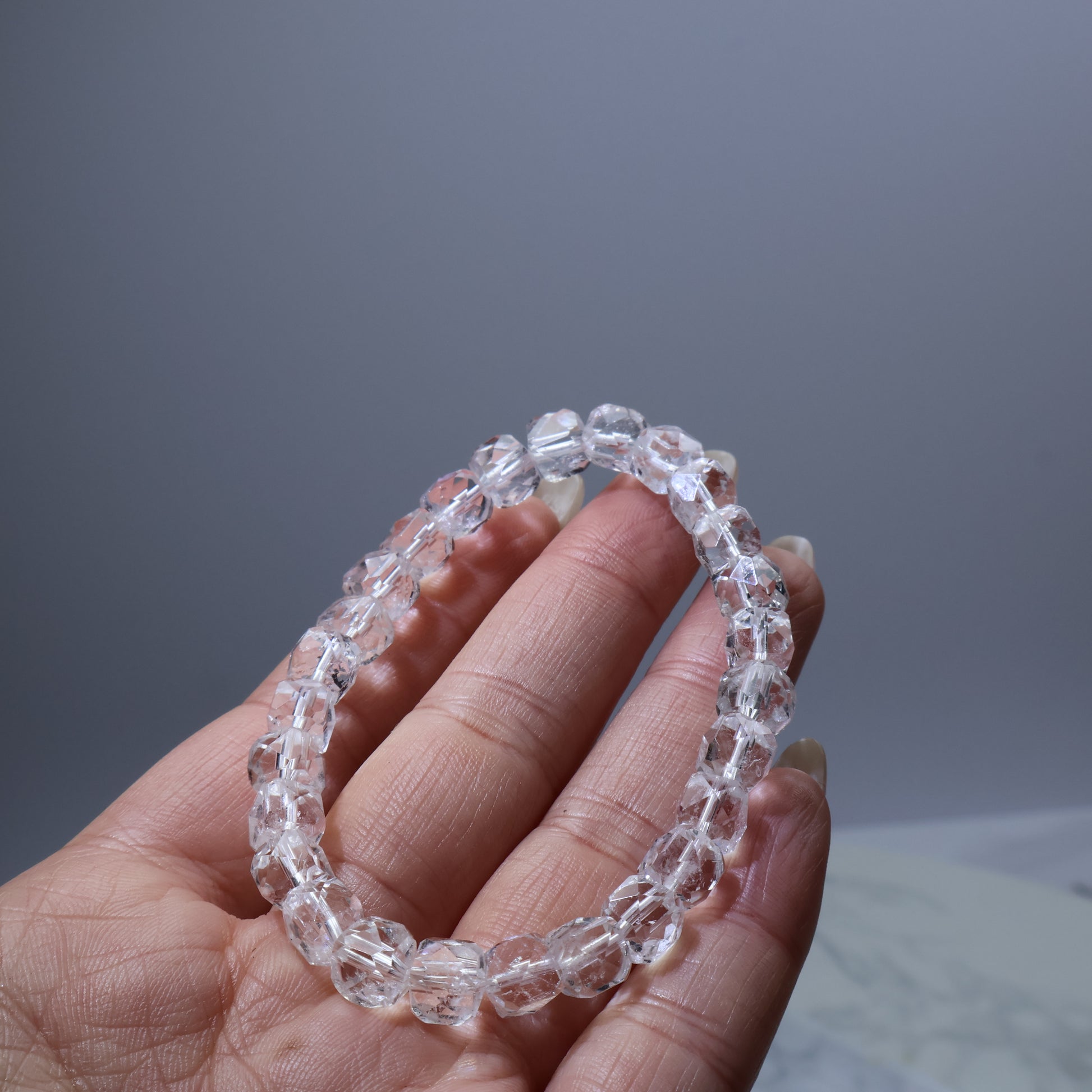 Handheld shot of small-cut clear quartz bracelet – elegant and minimal