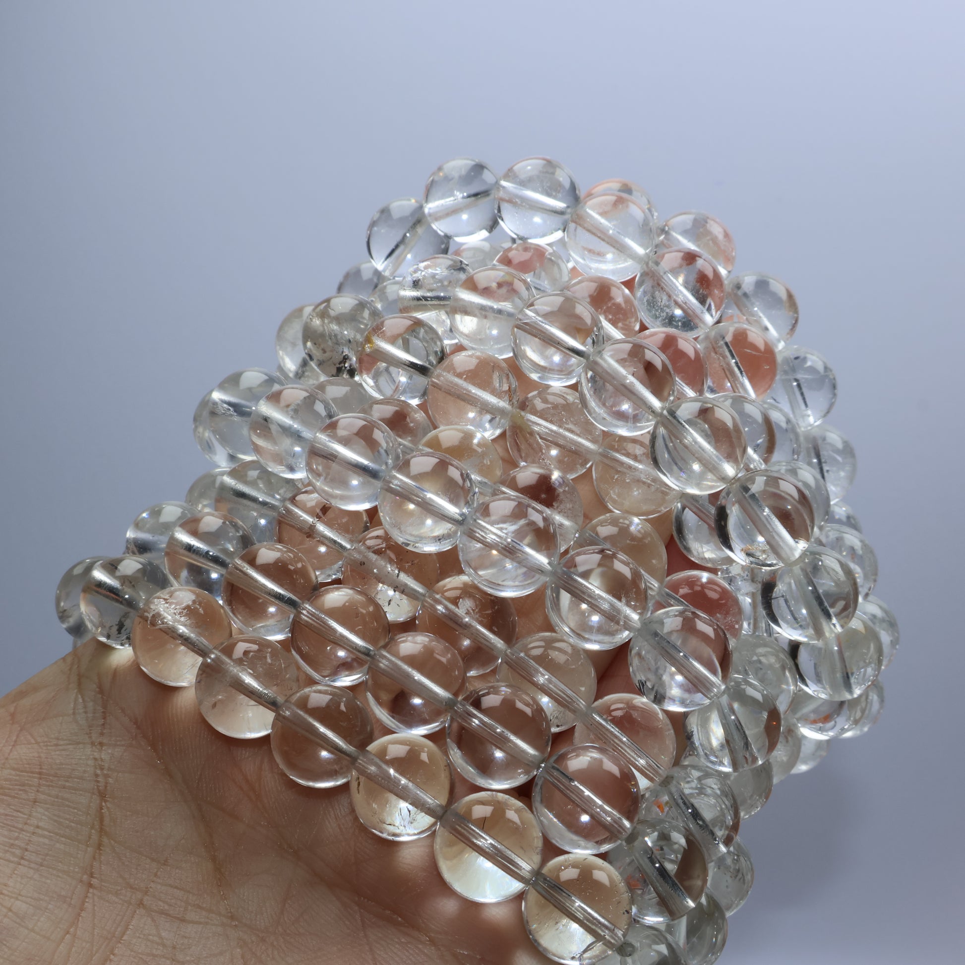 Stacked display of multiple clear quartz bracelets in natural lighting