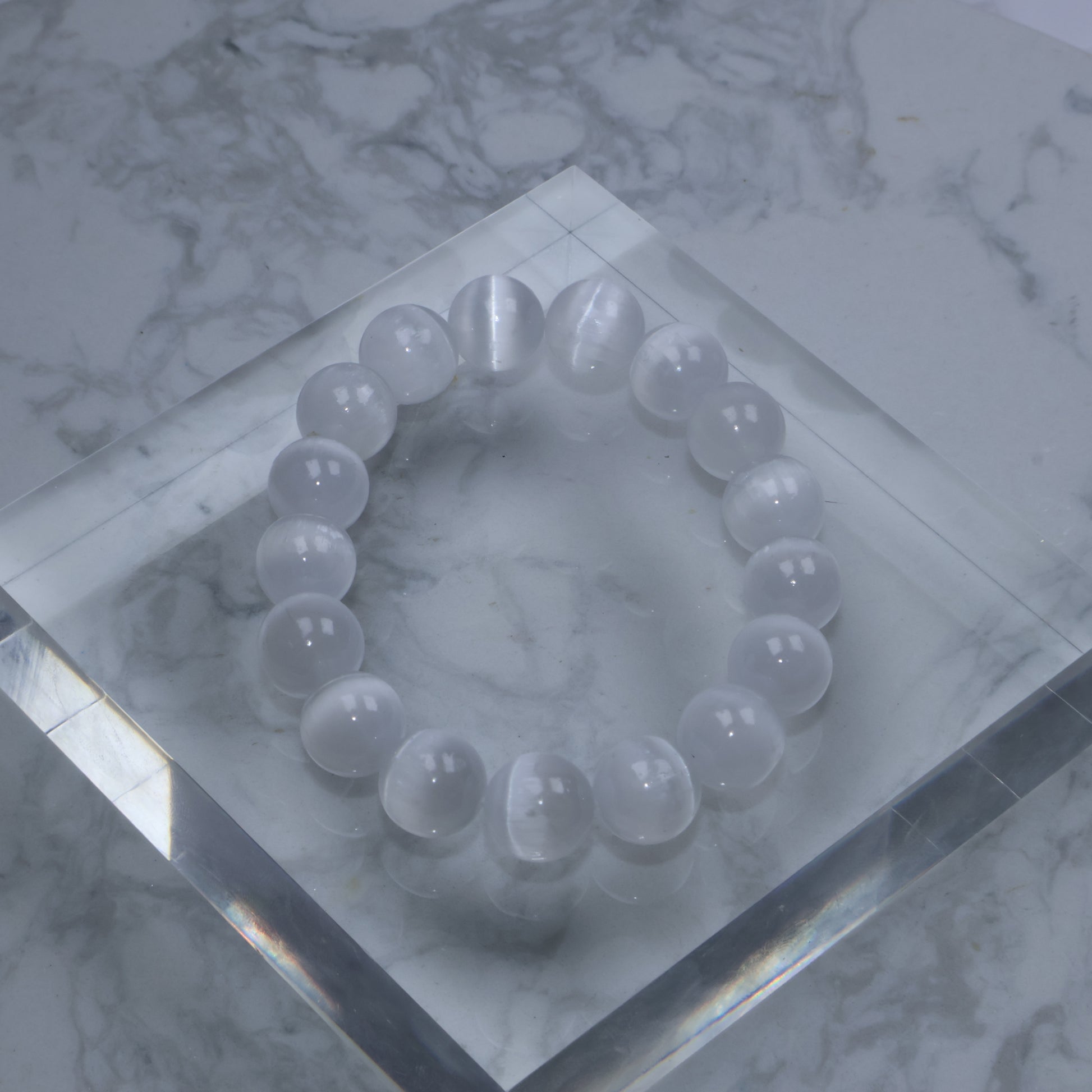 Luminous Selenite bracelet with silky glow resting on a clear cube