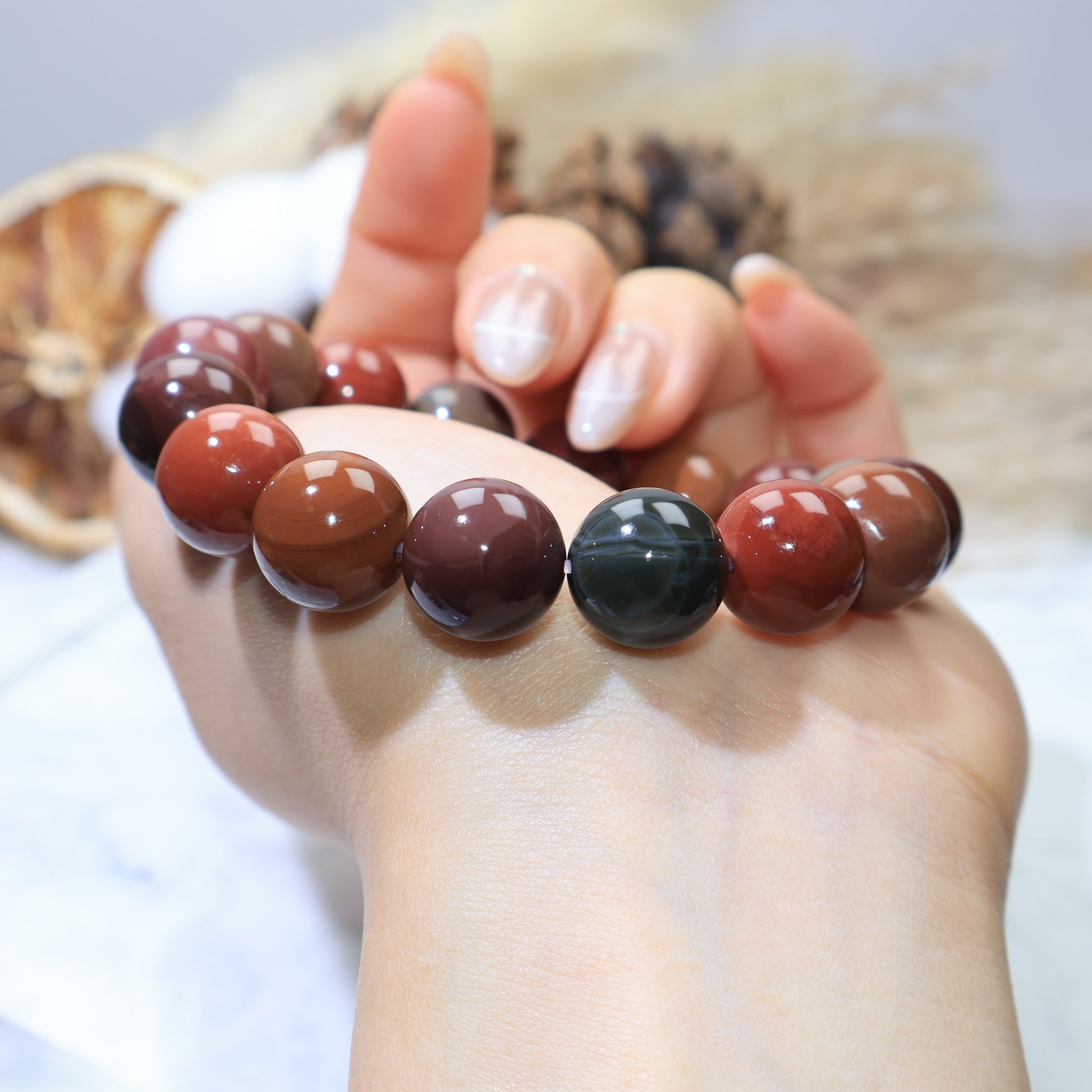 Side angle wrist shot showing deep green, earthy red, and brown beads