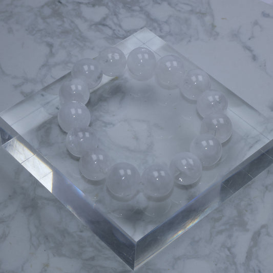 Top-down view of 15mm White Phantom Quartz bracelet on acrylic block, showing full circle of cloudy beads