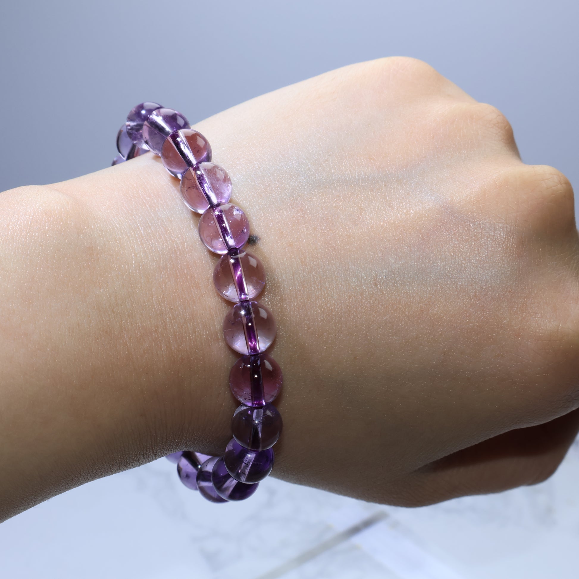 Wrist shot under bright light, beads glowing with dreamy purple tones