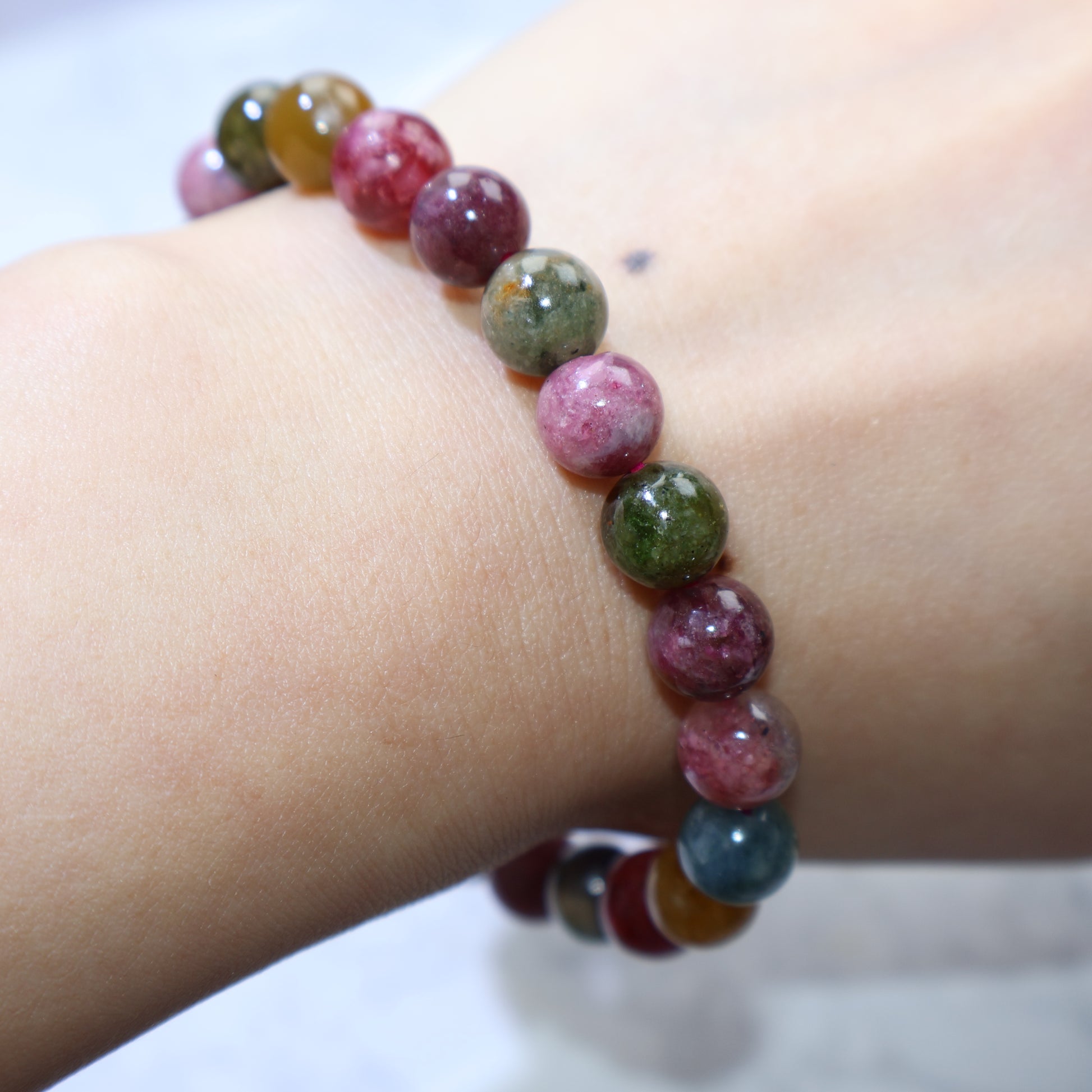 Bracelet draped over hand with soft lighting to enhance color depth