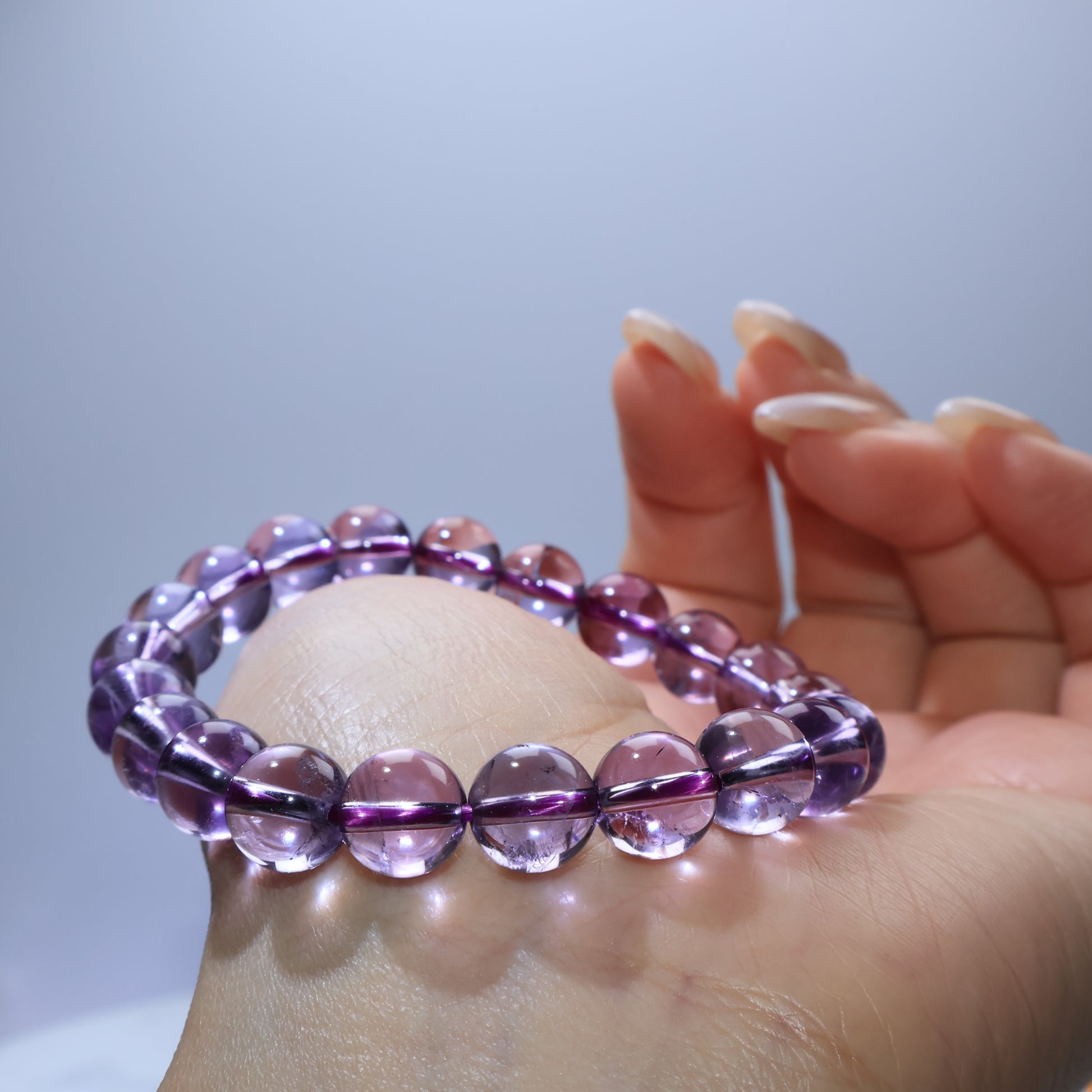 Handheld view of Dreamlight Amethyst bracelet, highlighting clarity and even bead size