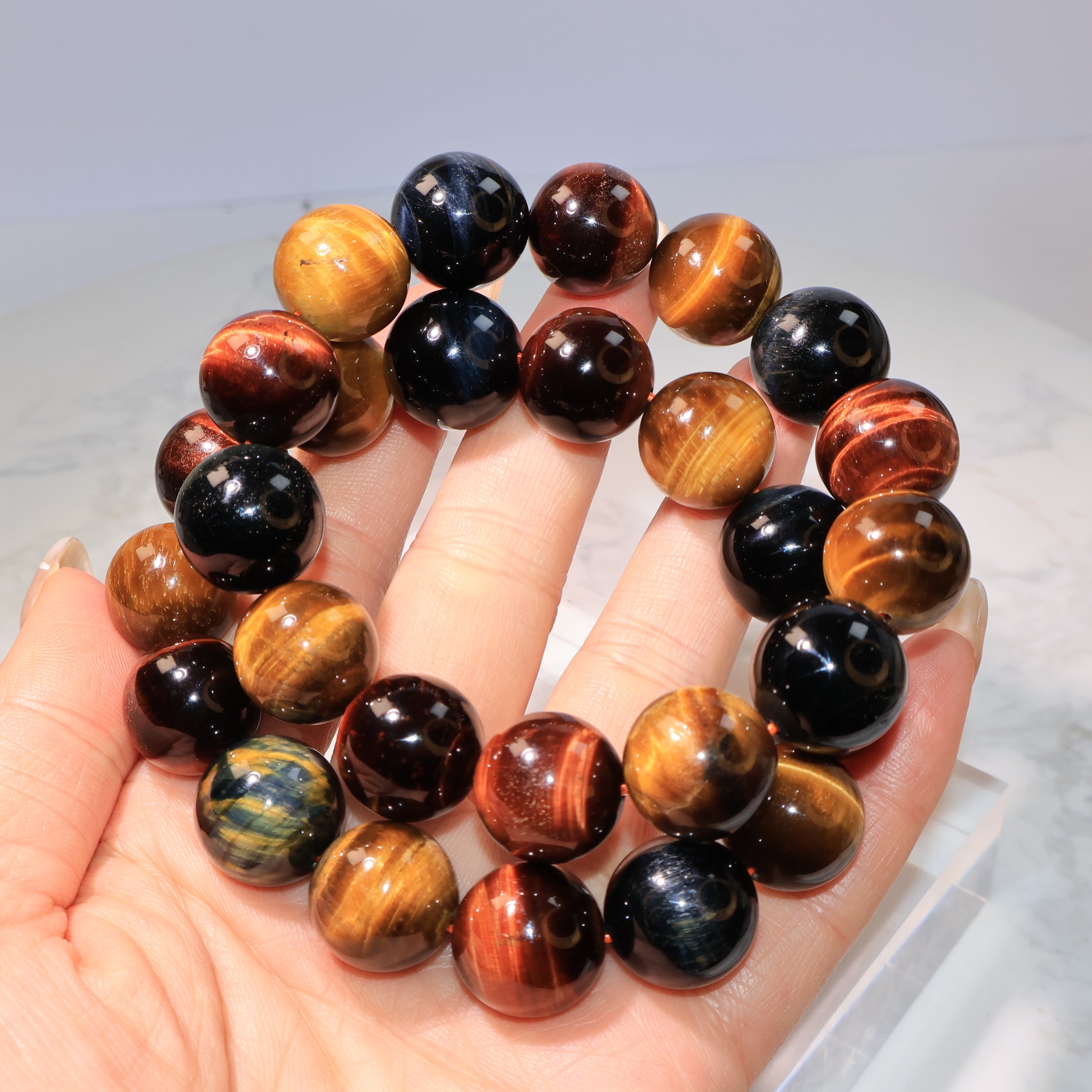 Two Tiger Eye bracelets stacked together in hand, showing rich color variation.