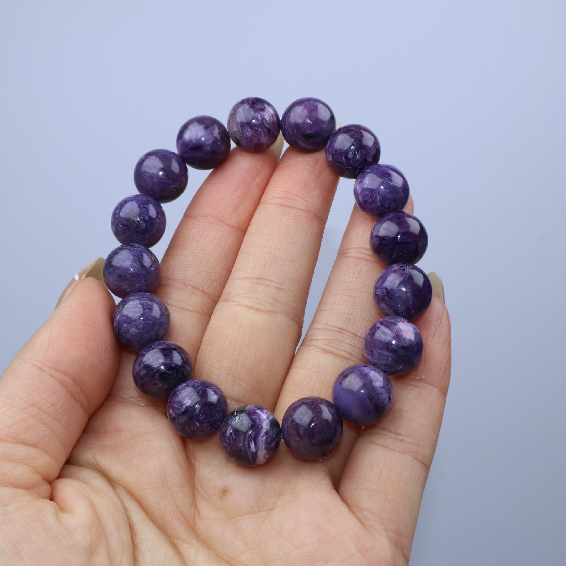 Handheld view of 12mm Charoite bracelet showing bead textures