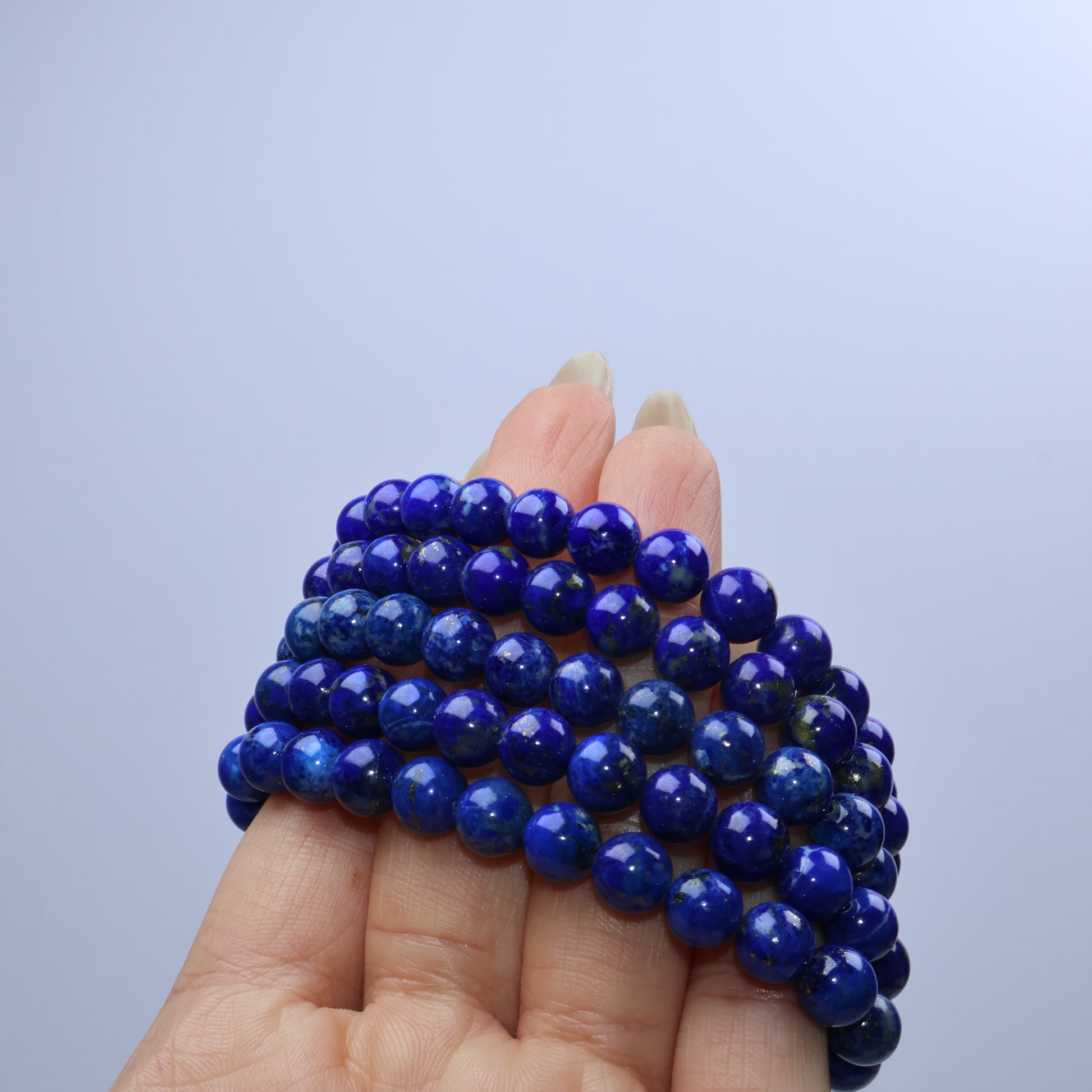Bunched view of multiple lapis lazuli bracelets in hand