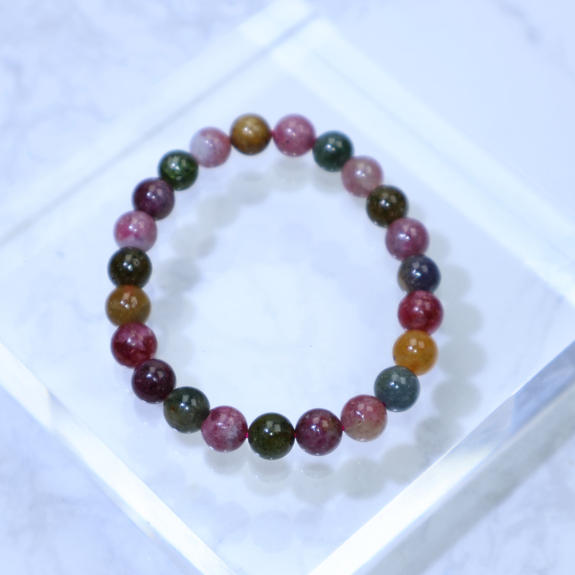 Handheld view of 8mm multicolor tourmaline bracelet showing pink, green, yellow and blue beads