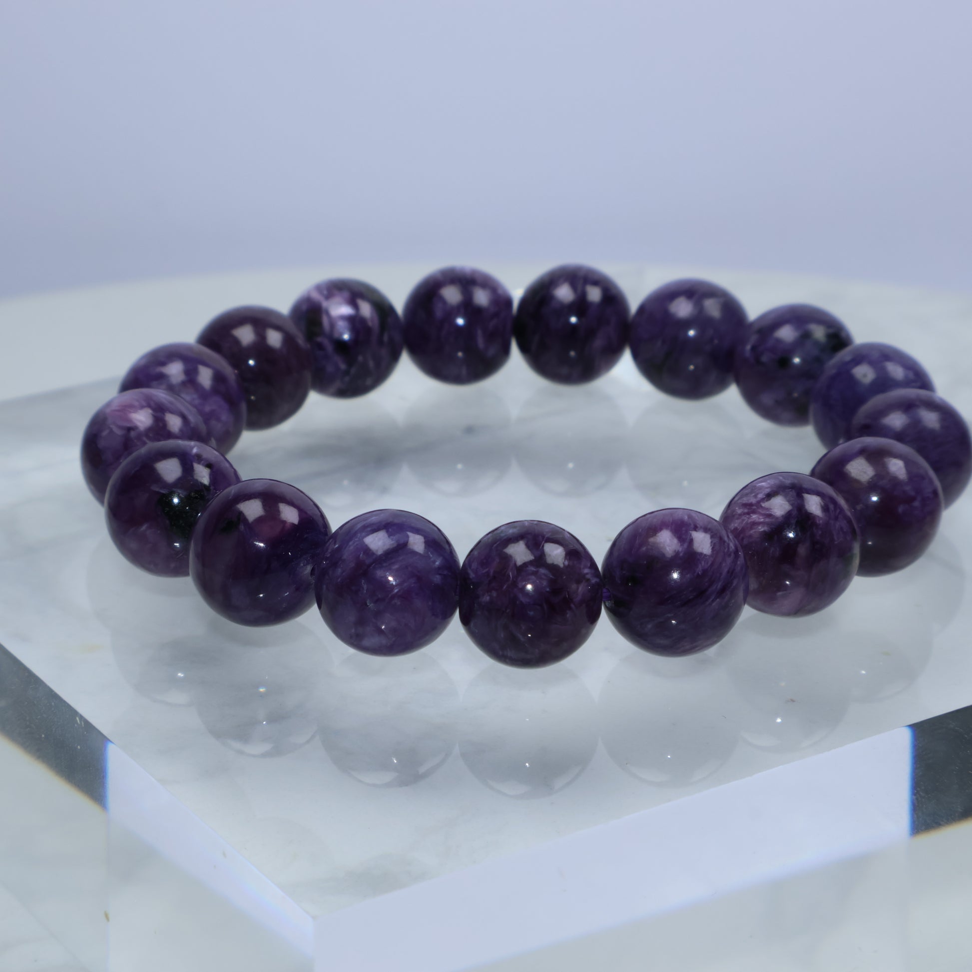 Natural Charoite bracelet on white marble platform, capturing color depth