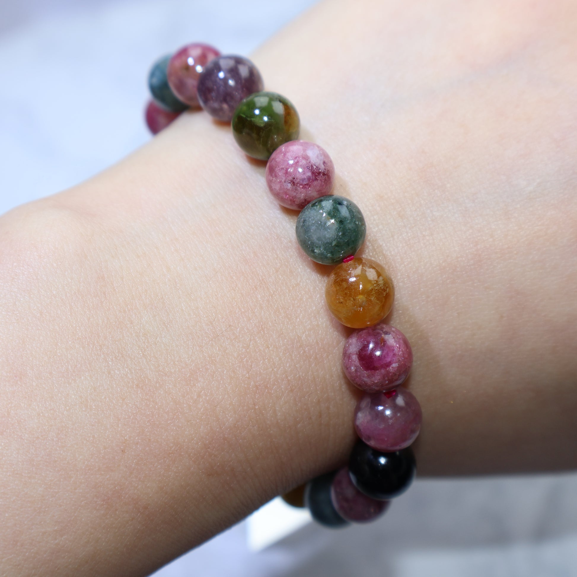Bracelet draped over hand with soft lighting to reveal color depth