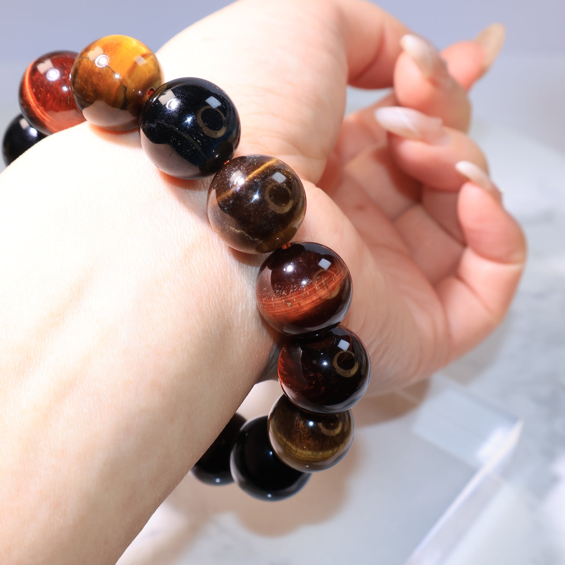 Wrist shot showing multiple beads reflecting golden and red hues.