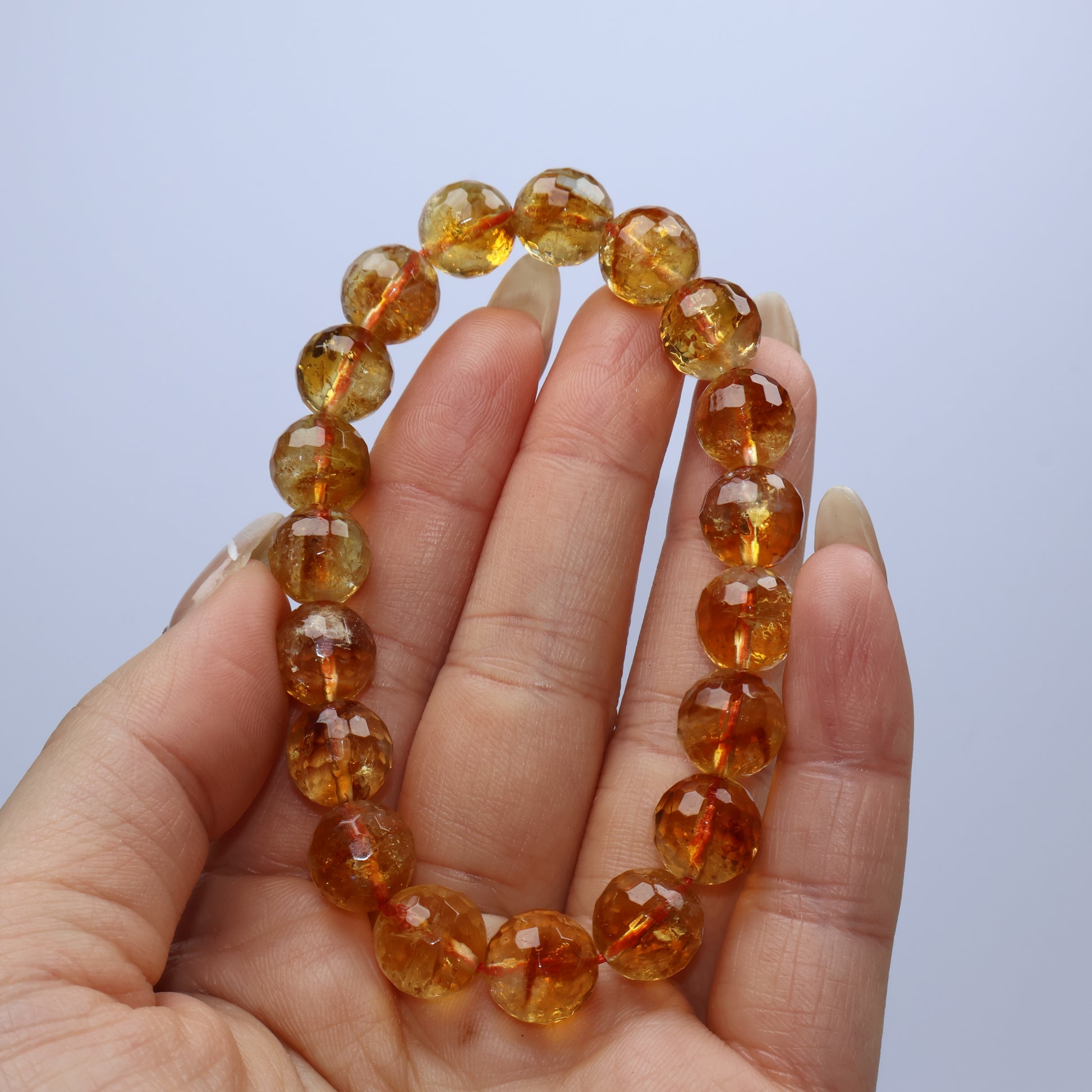 Handheld close-up showing warm-toned faceted citrine beads with natural inclusions