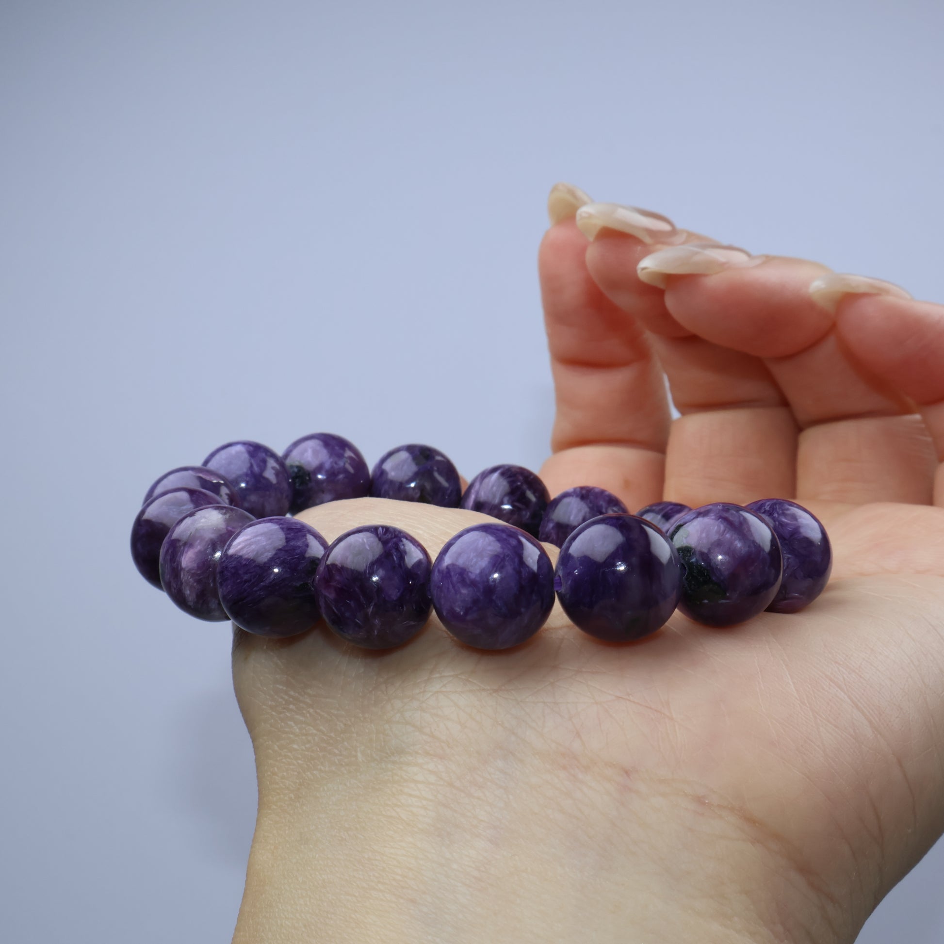 Side palm shot of Charoite bracelet to reveal luster and curvature