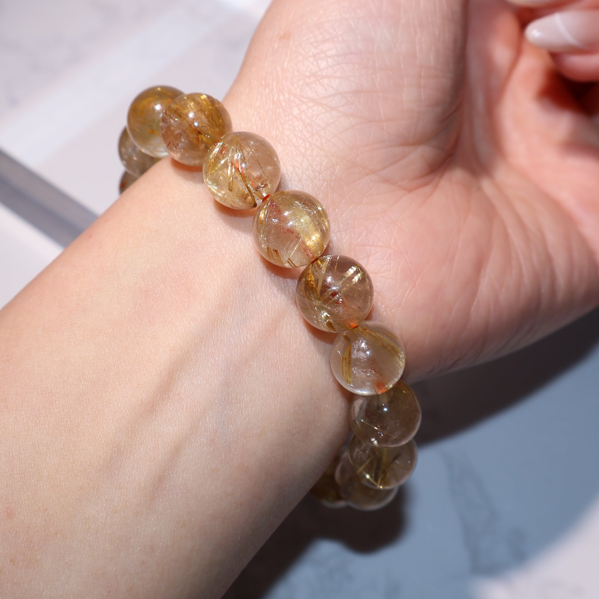 Worn on wrist – golden rutilated quartz bracelet in soft lighting