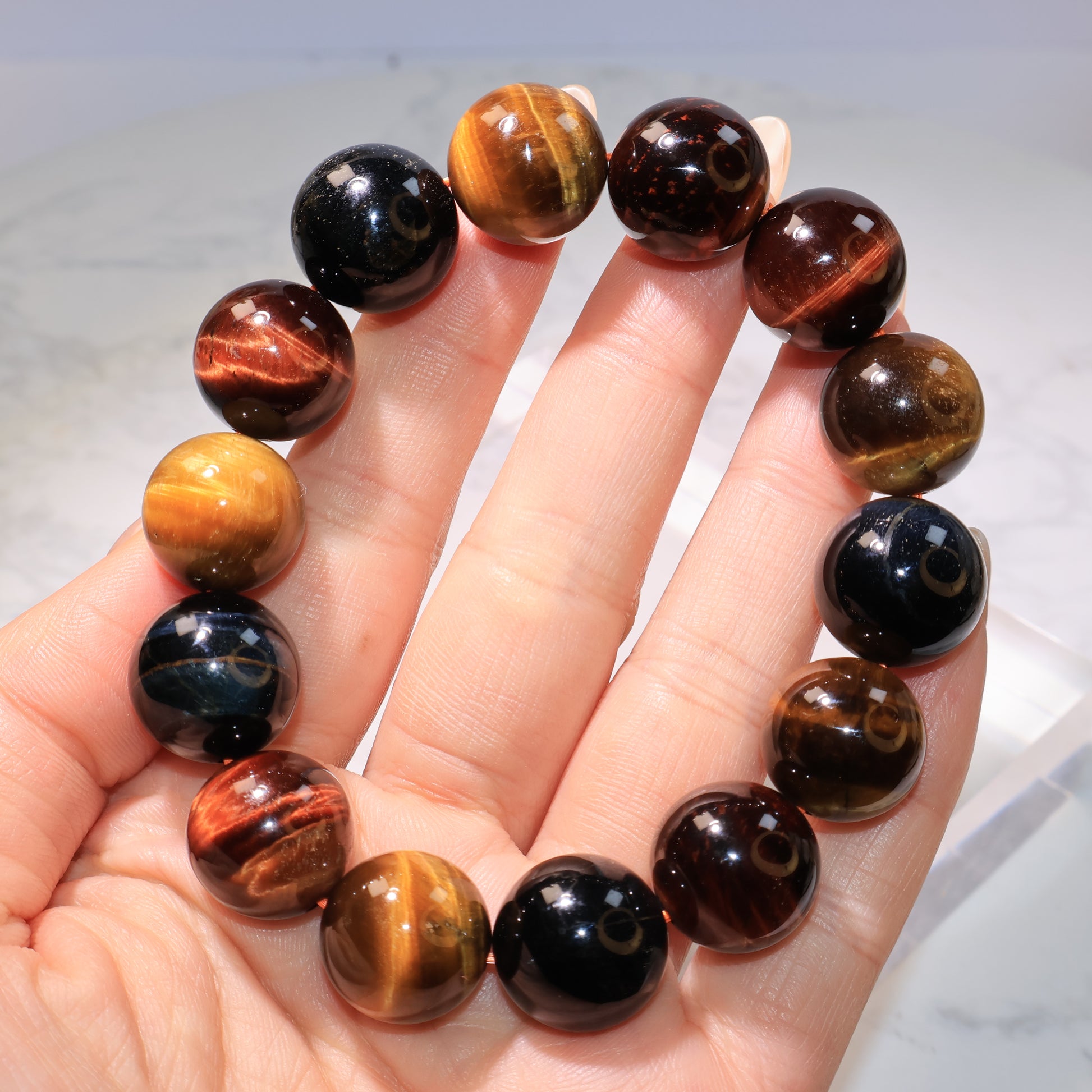 Close-up of the bracelet held in hand showing the shiny 15–16mm beads.