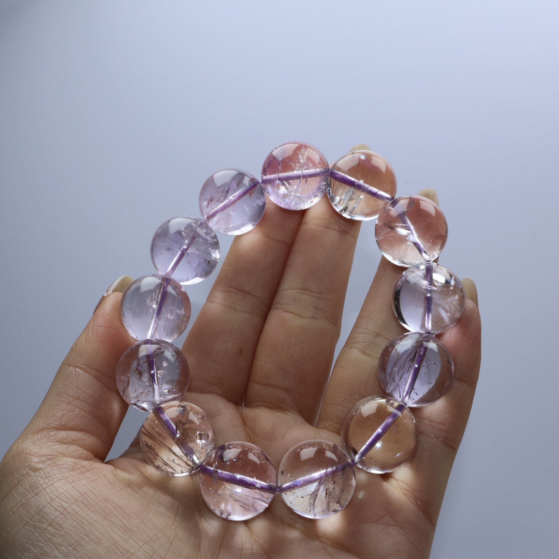 Handheld view of light purple amethyst beads with internal fissures