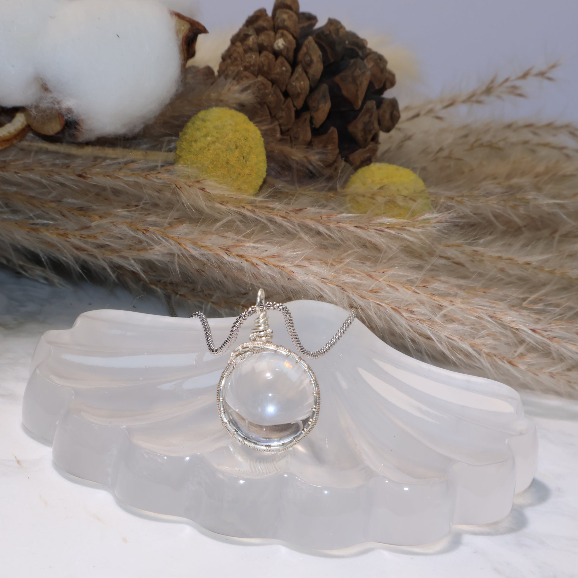 Front view of the pendant on the shell stand, highlighting the clarity and handmade wire wrapping details.