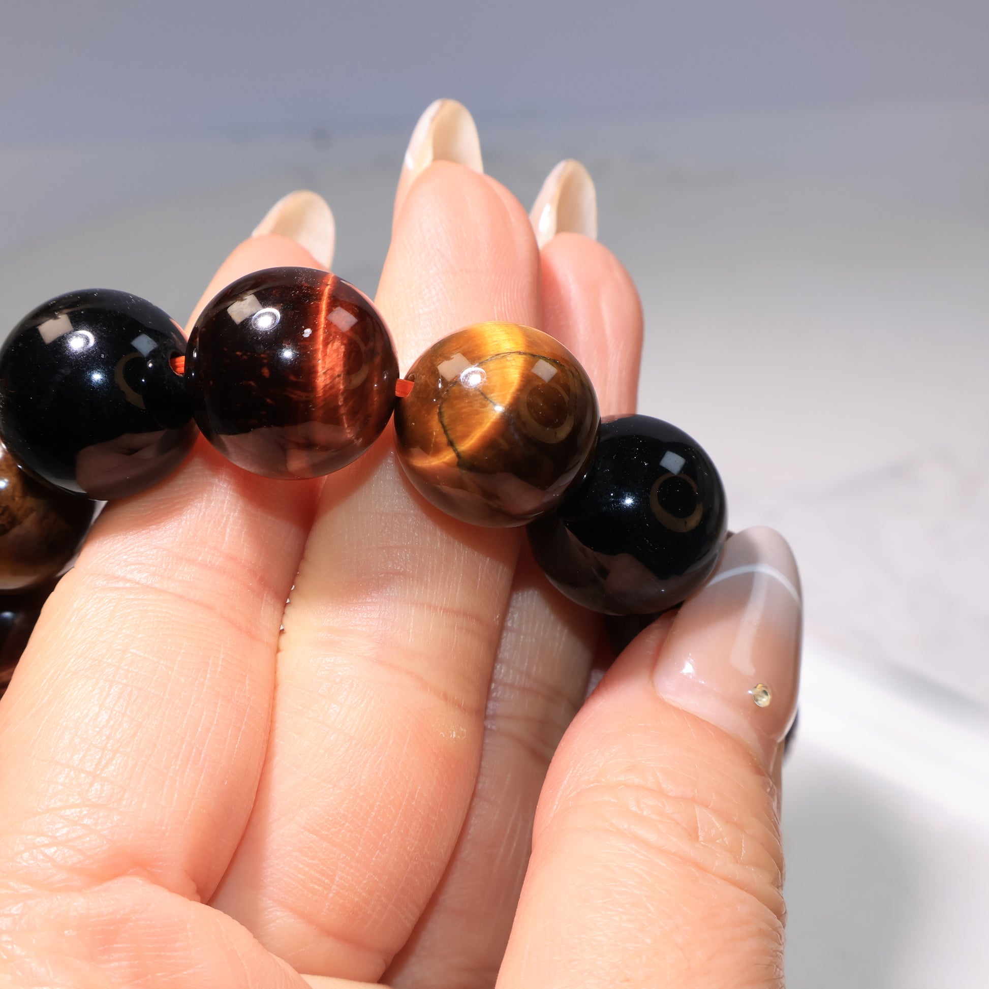 Bracelet worn on wrist under bright light, with beads glowing in different shades.
