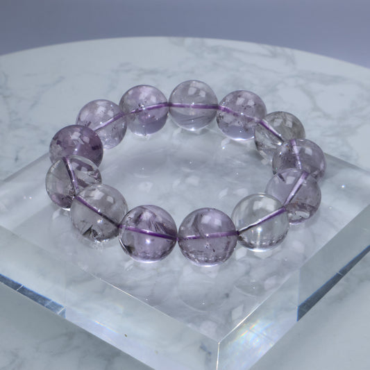 Close-up of translucent 17mm amethyst bracelet on a clear acrylic display