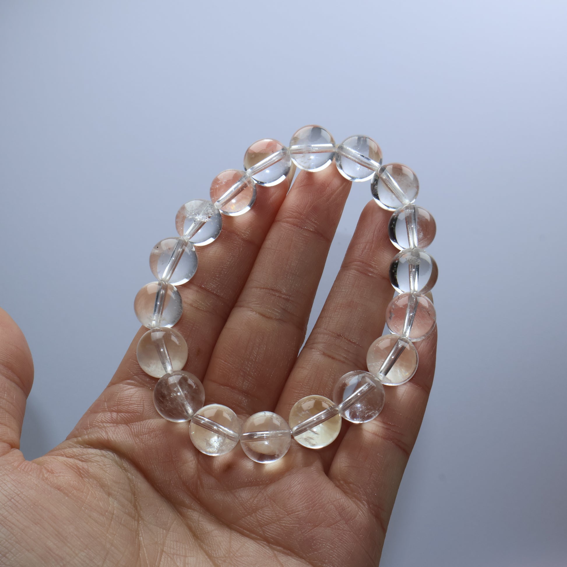 Handheld view of clear quartz bracelet showing slight inclusions and natural clarity
