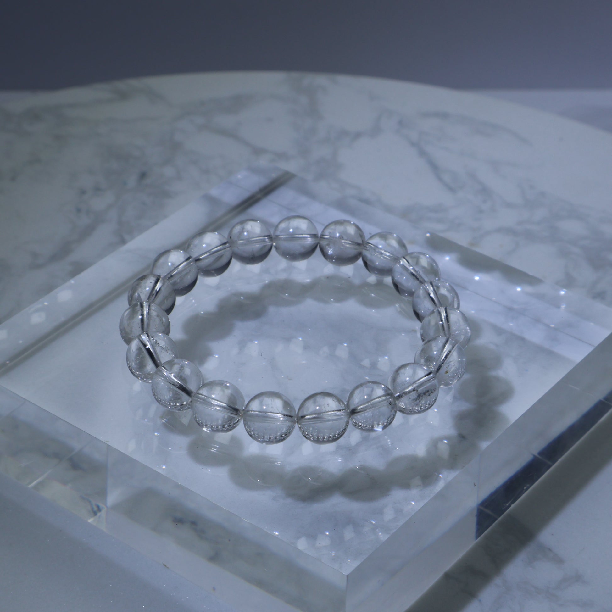 Clean clear quartz bracelet on acrylic block – 10mm starter crystal