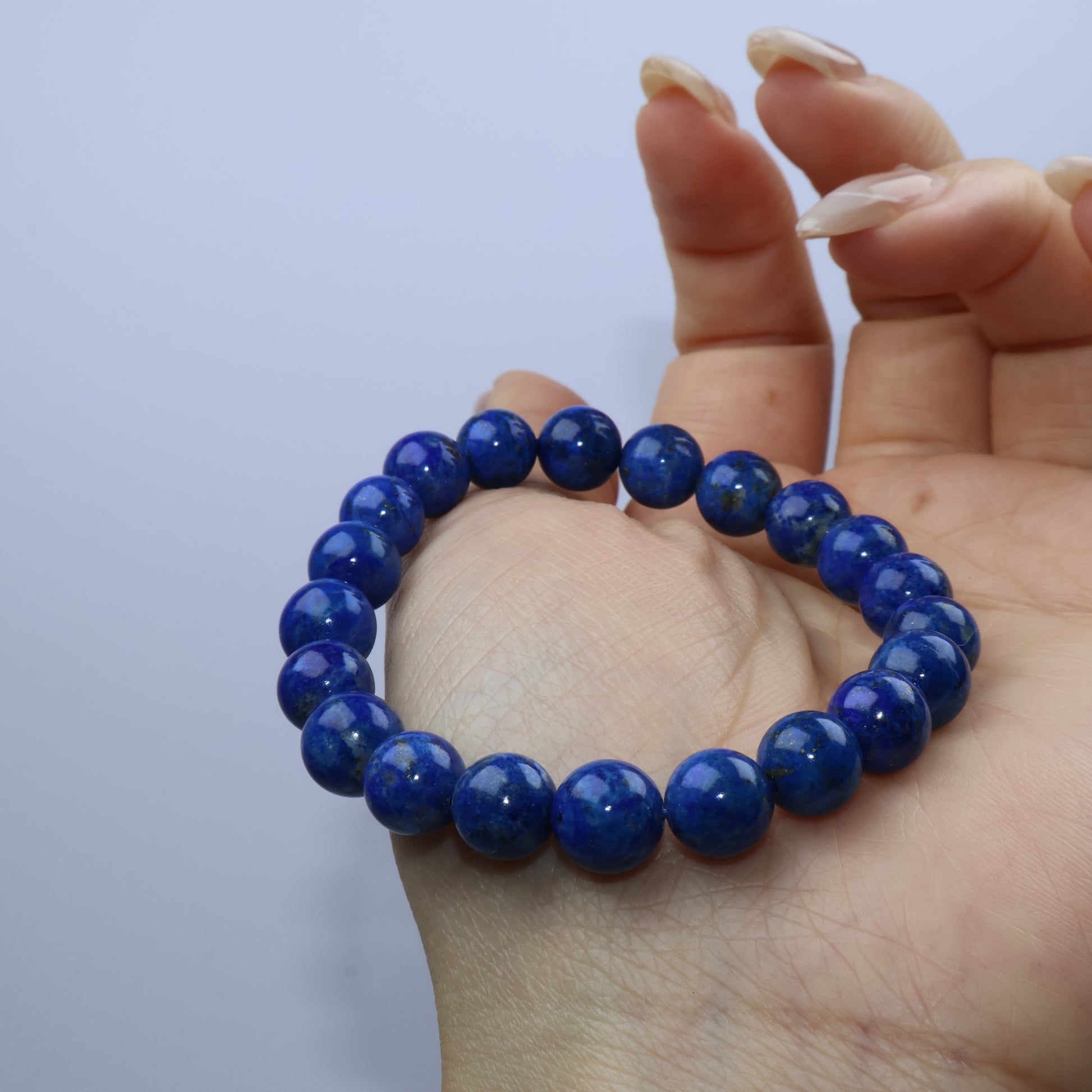 Palm view of Lapis Lazuli bracelet showing smooth round beads with rich royal blue tones
