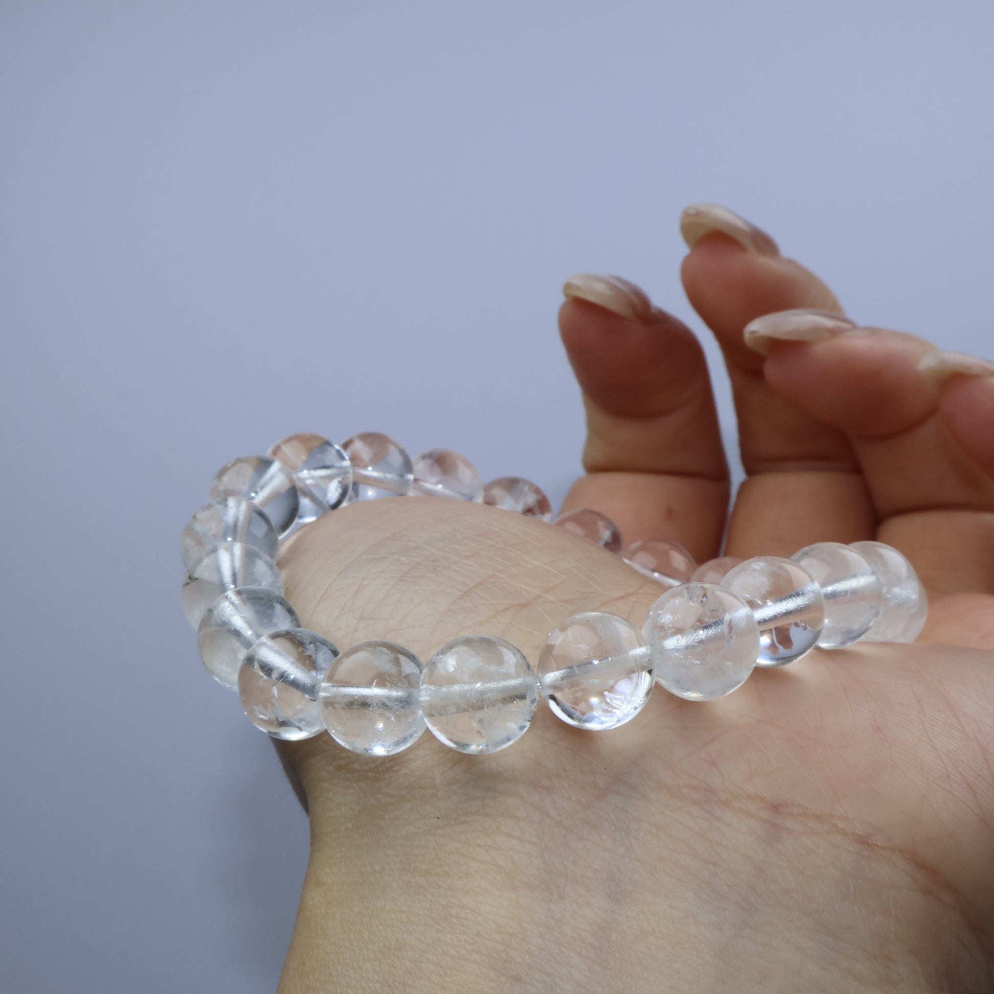 Side angle of Clear Quartz bracelet draped over hand, showing bead clarity and natural inclusions