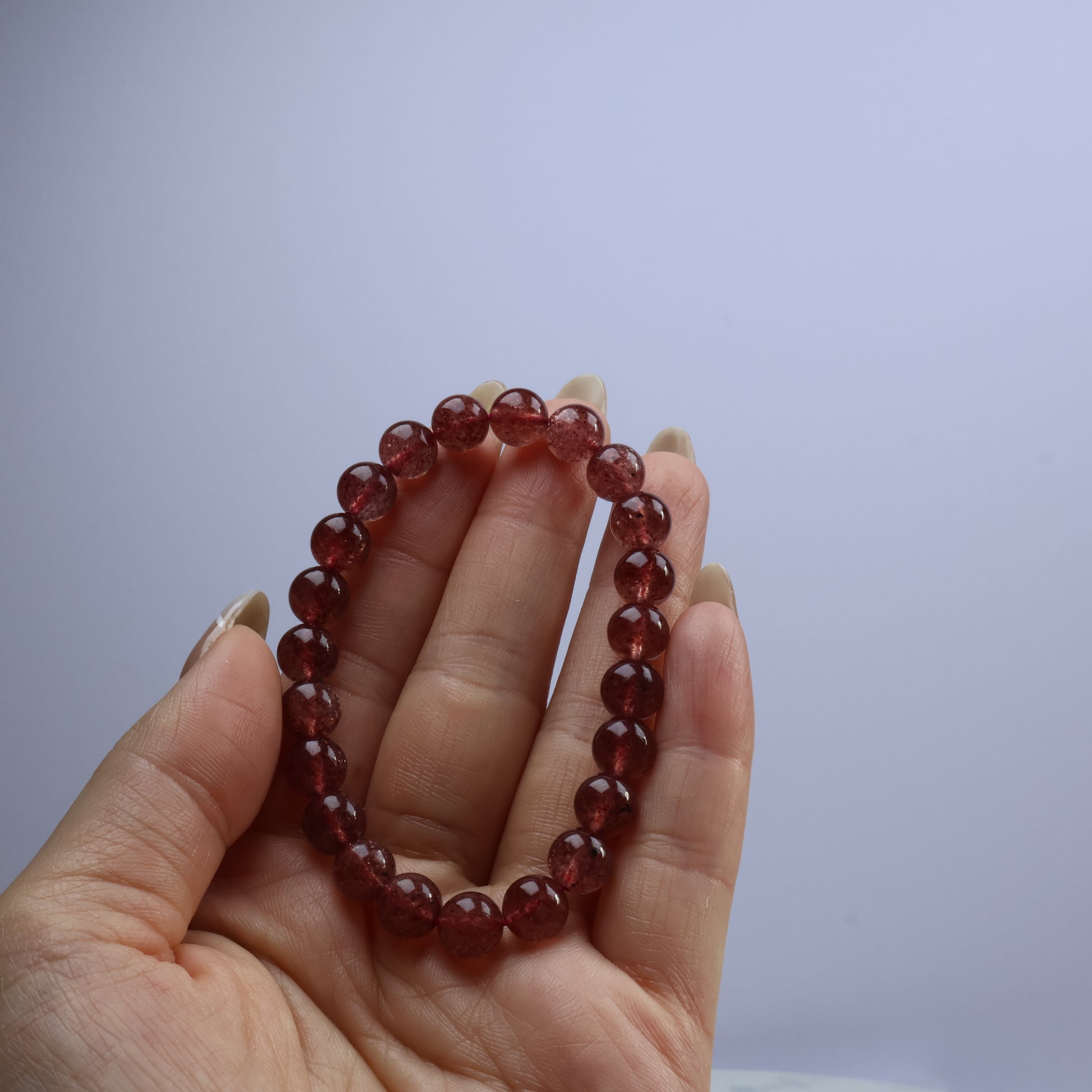 Handheld view of Strawberry Quartz bracelet showing vibrant red crystal beads