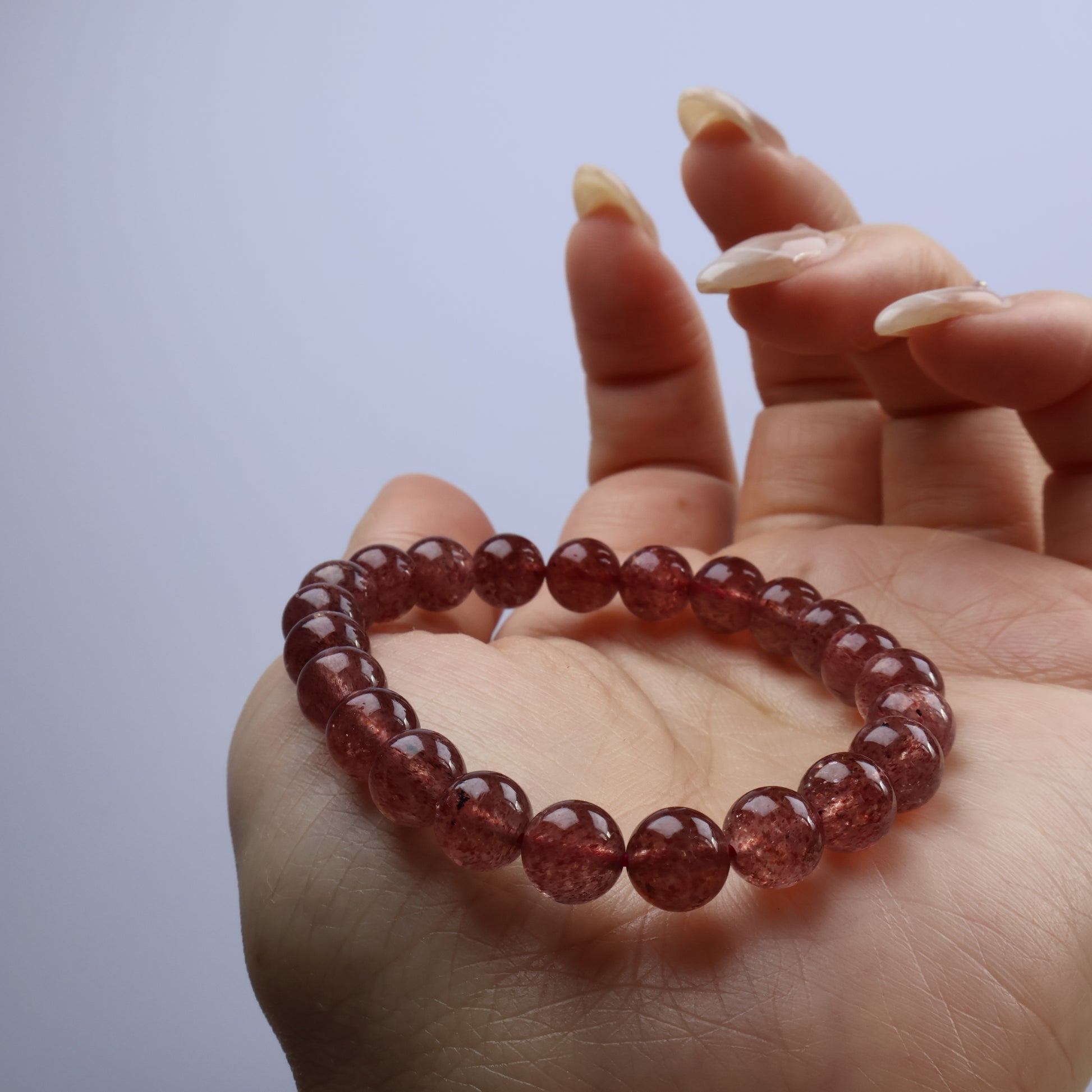 Wrist shot showing natural warm tone of Strawberry Quartz under soft light