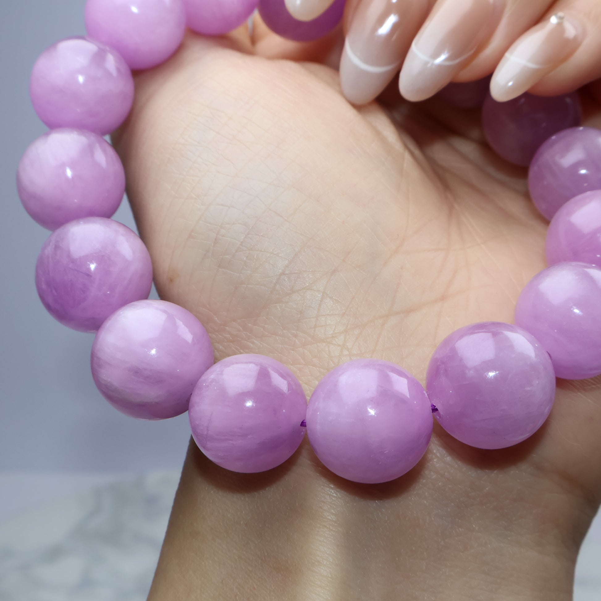 Side hand angle holding the bracelet to emphasize luster and roundness