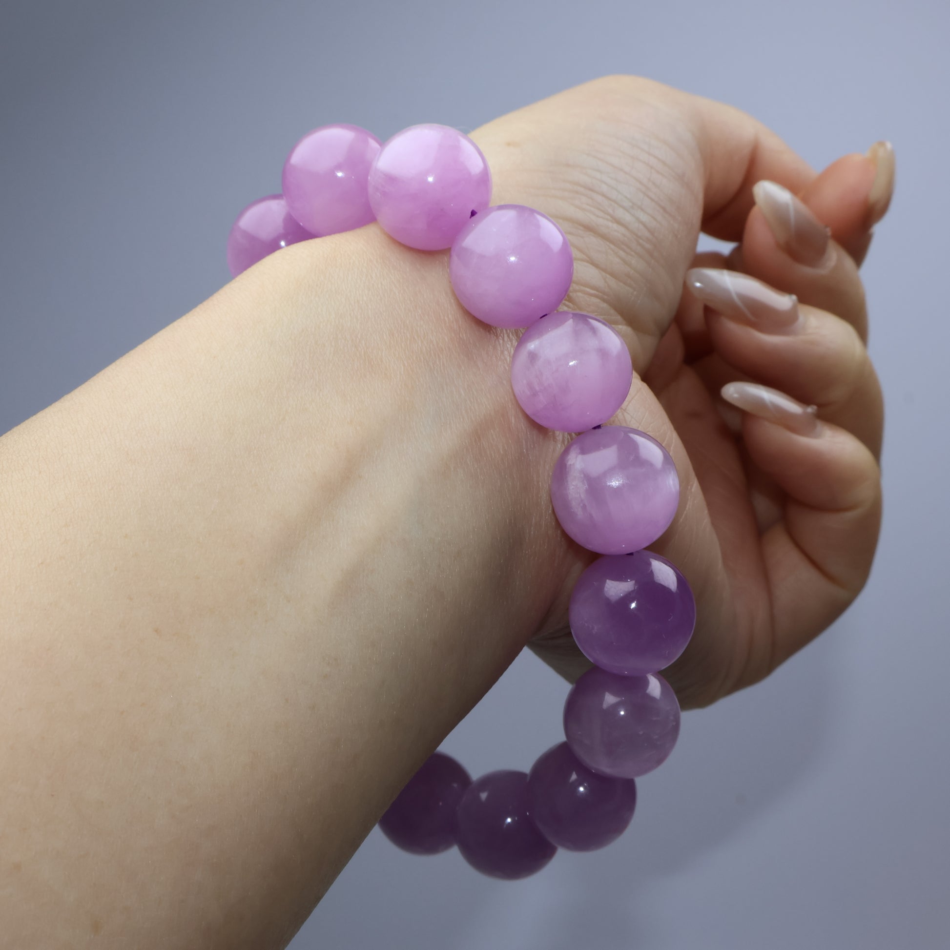 Close-up of Lepidolite beads on wrist, highlighting gentle chatoyancy and texture