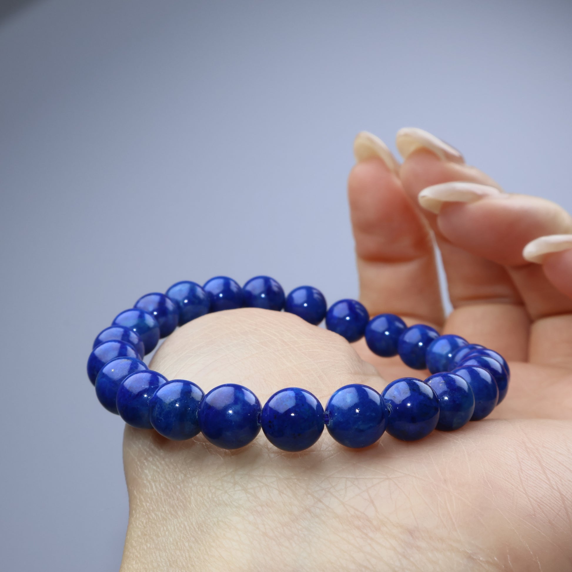 Side view of a Lapis Lazuli bracelet draped over the hand, showing rich color and luster
