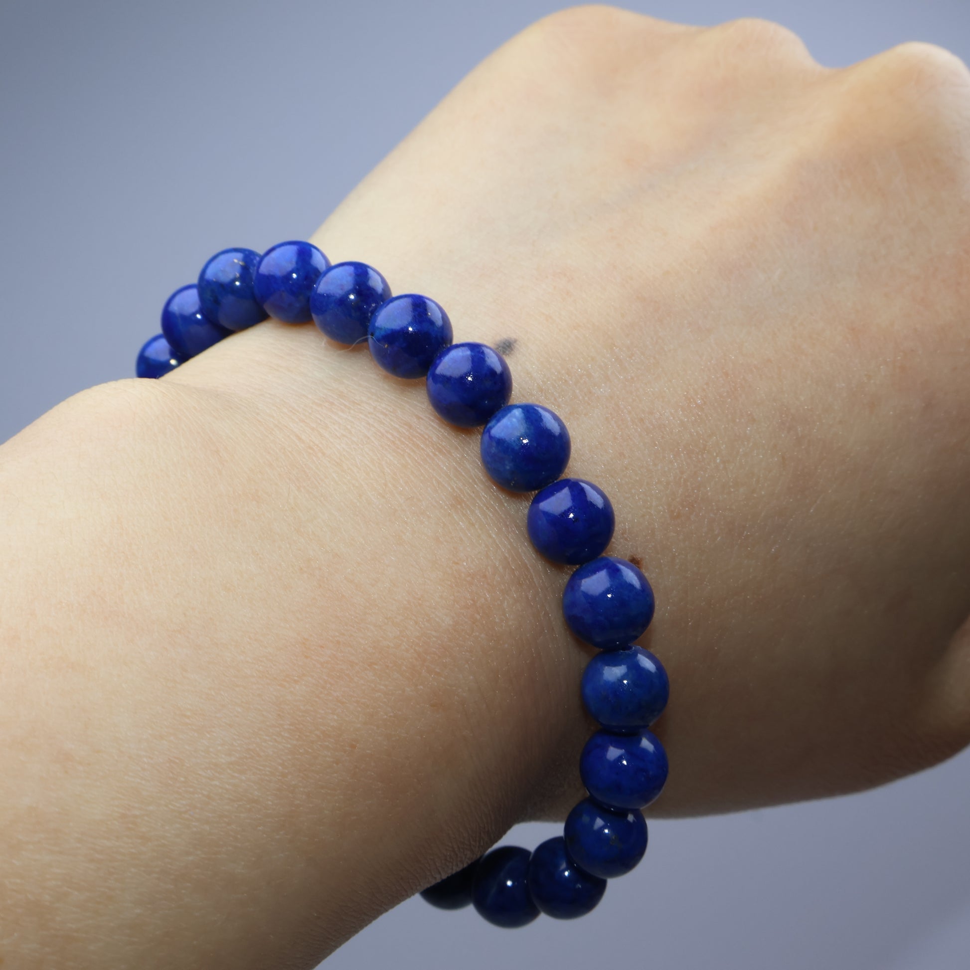 Wrist shot showing the dark blue bracelet worn snugly on light skin
