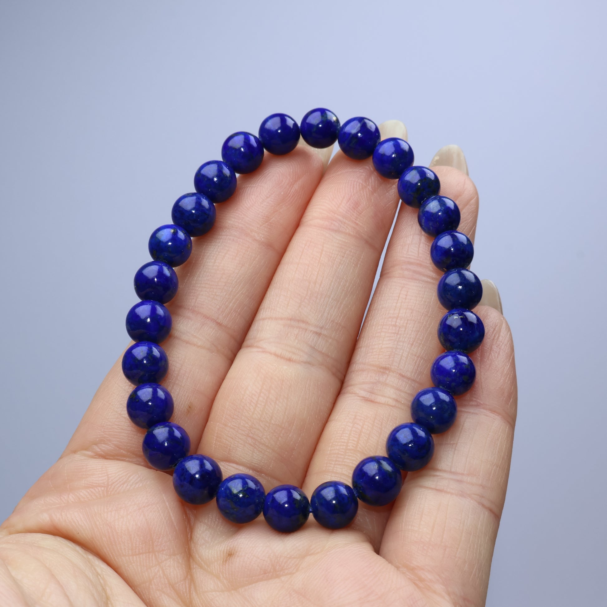 Handheld view of 7mm Lapis Lazuli bracelet showing rich, clean blue tone
