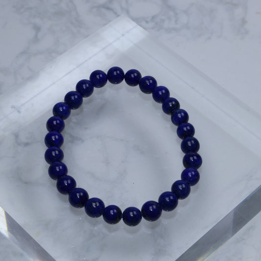 Top-down photo of Lapis Lazuli bracelet with deep royal blue color on acrylic block