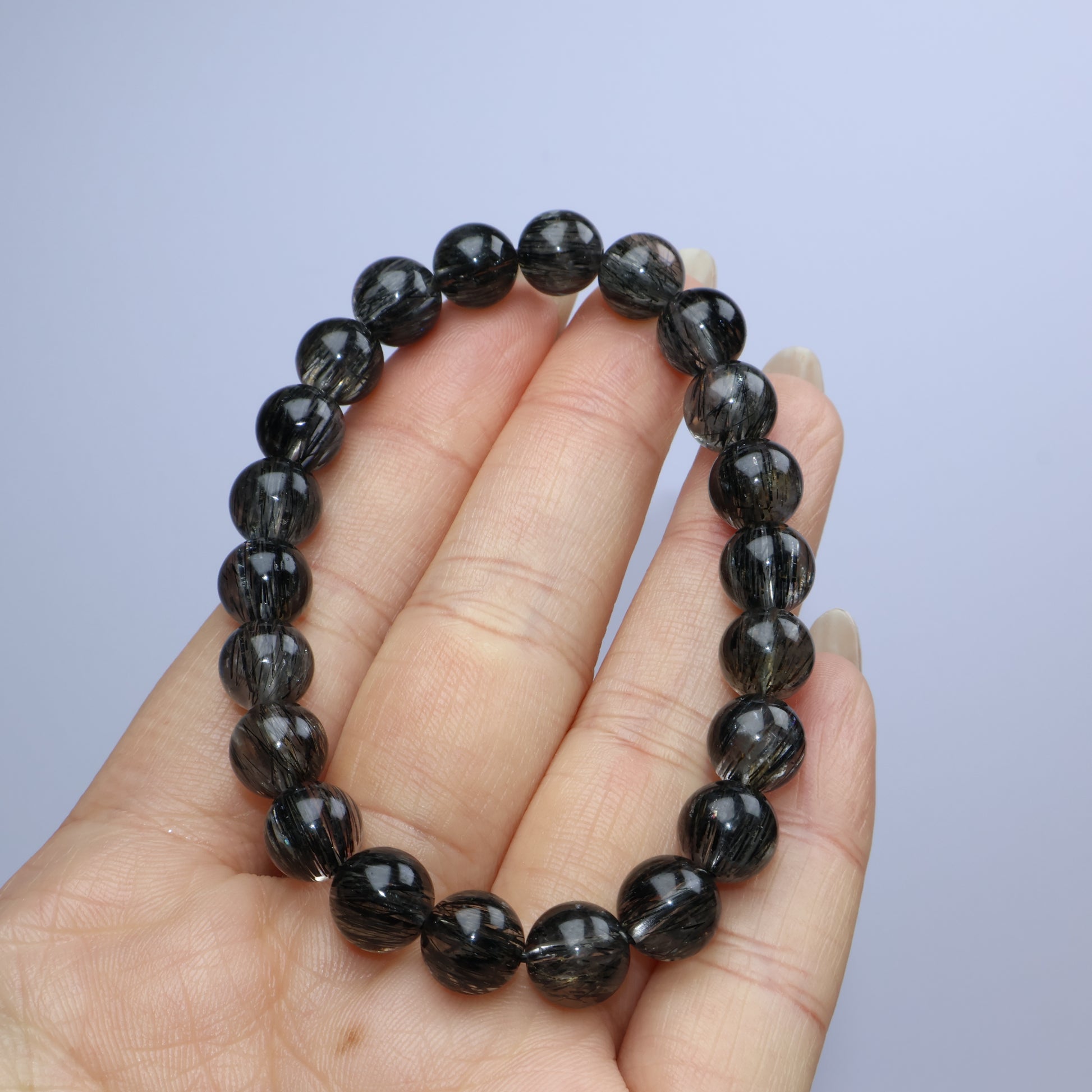 Handheld view with bracelet resting neatly on fingers, highlighting internal patterns