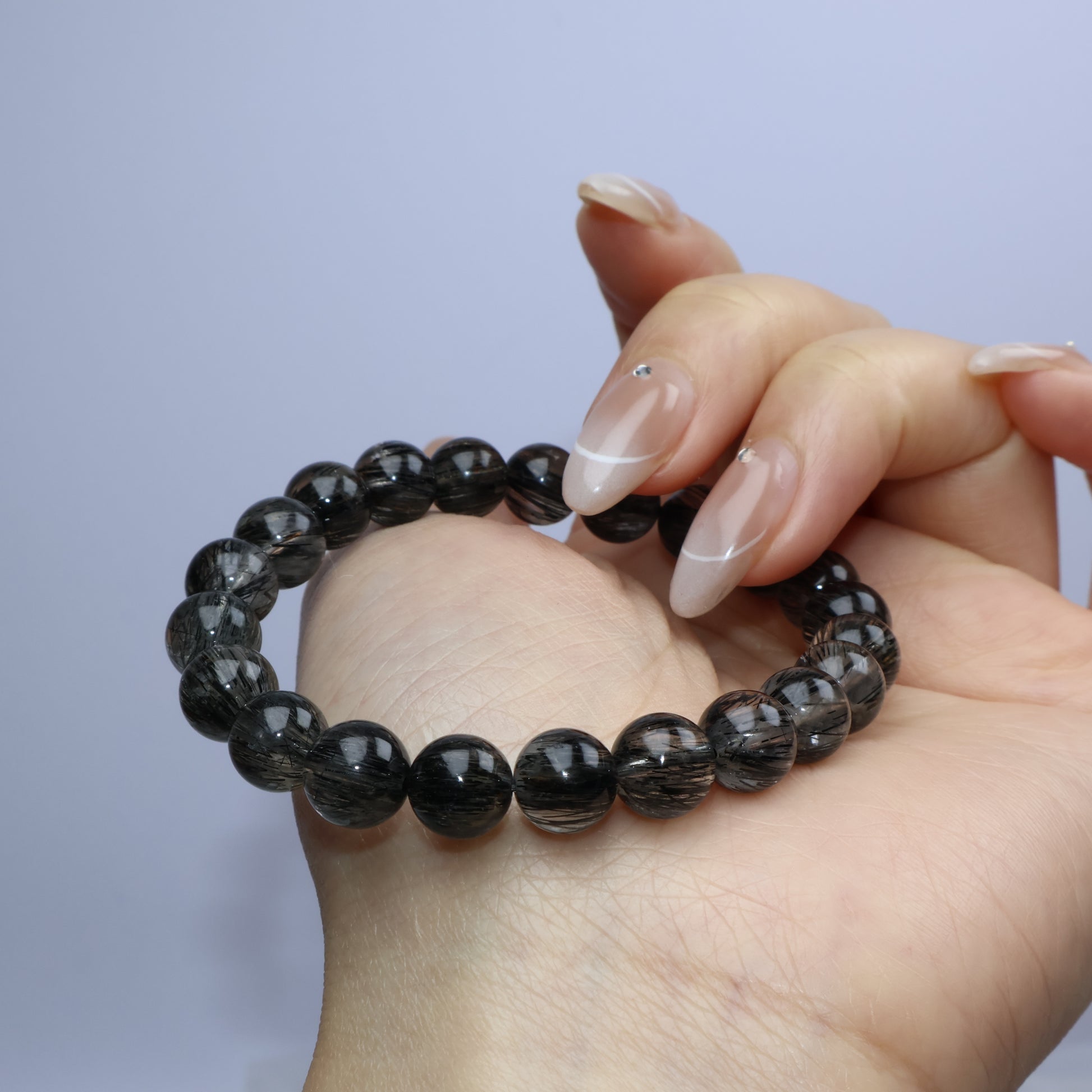 Lightly curled hand holding the bracelet to highlight bead uniformity