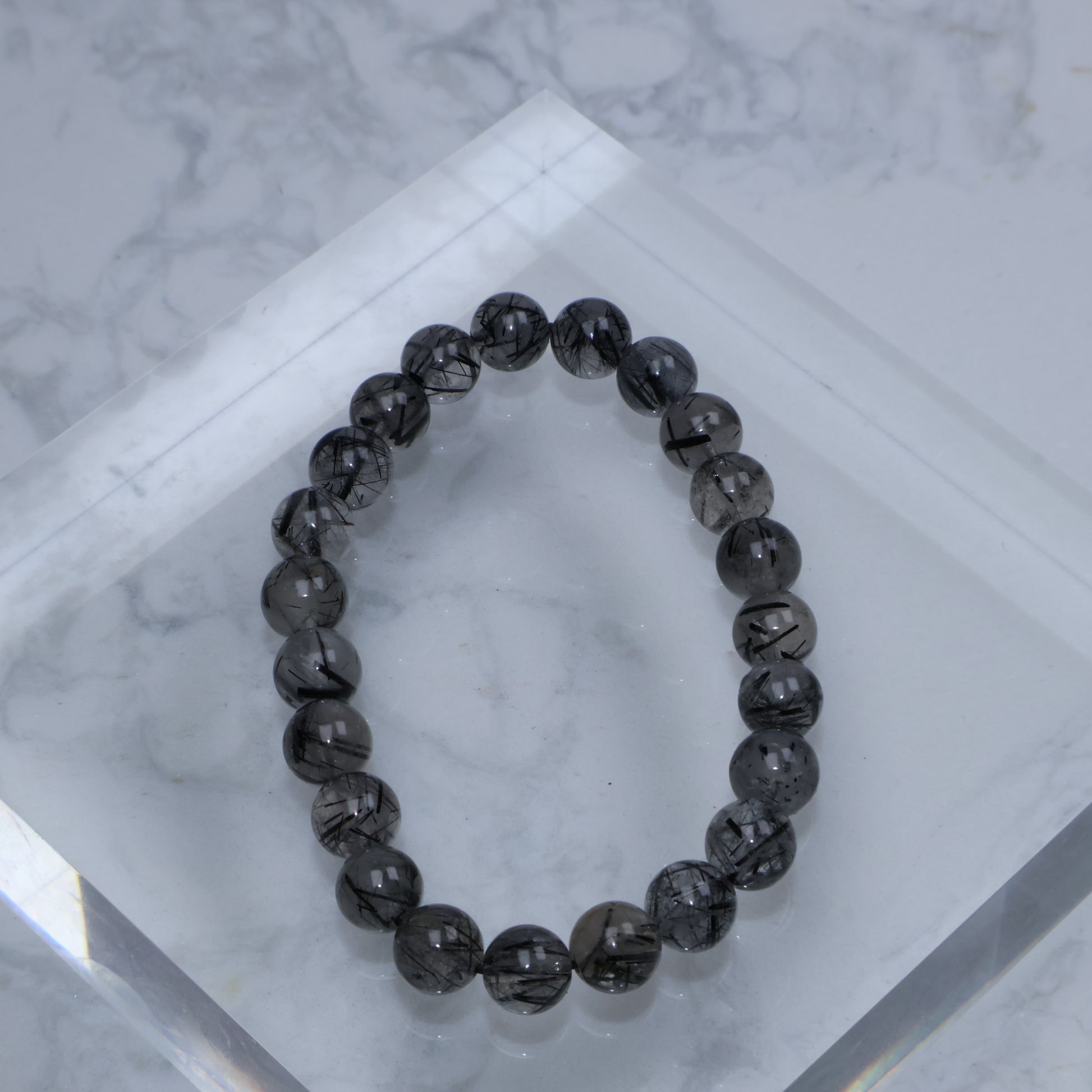Top-down view of Black Rutilated Quartz bracelet with visible rutile strands on clear quartz surface