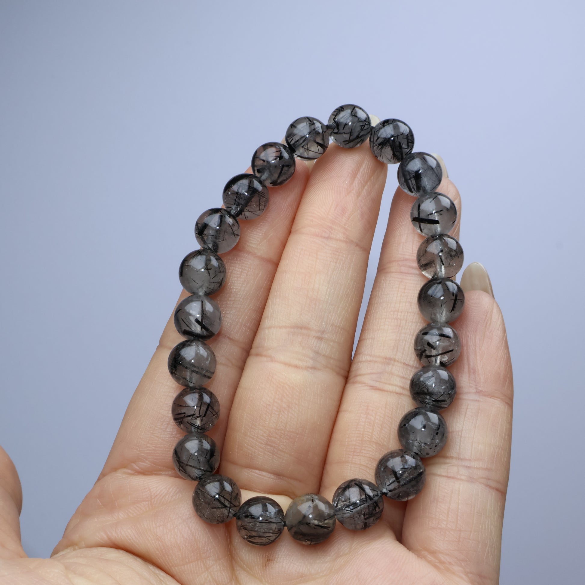 Handheld shot showing uniform 8mm beads with internal black needle inclusions