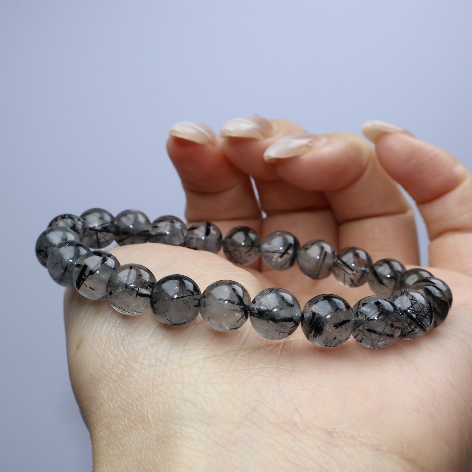 Side angle resting on hand to show depth and luster of the rutile inclusions