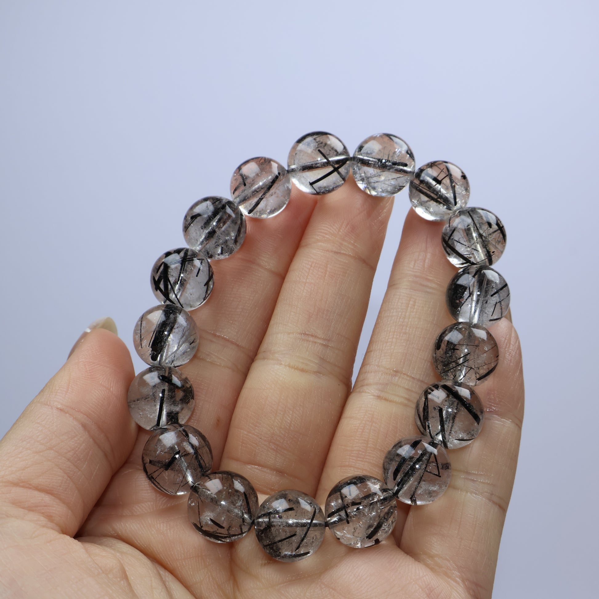 Handheld shot showing full view of bracelet with visible cotton inclusions and glossy surface