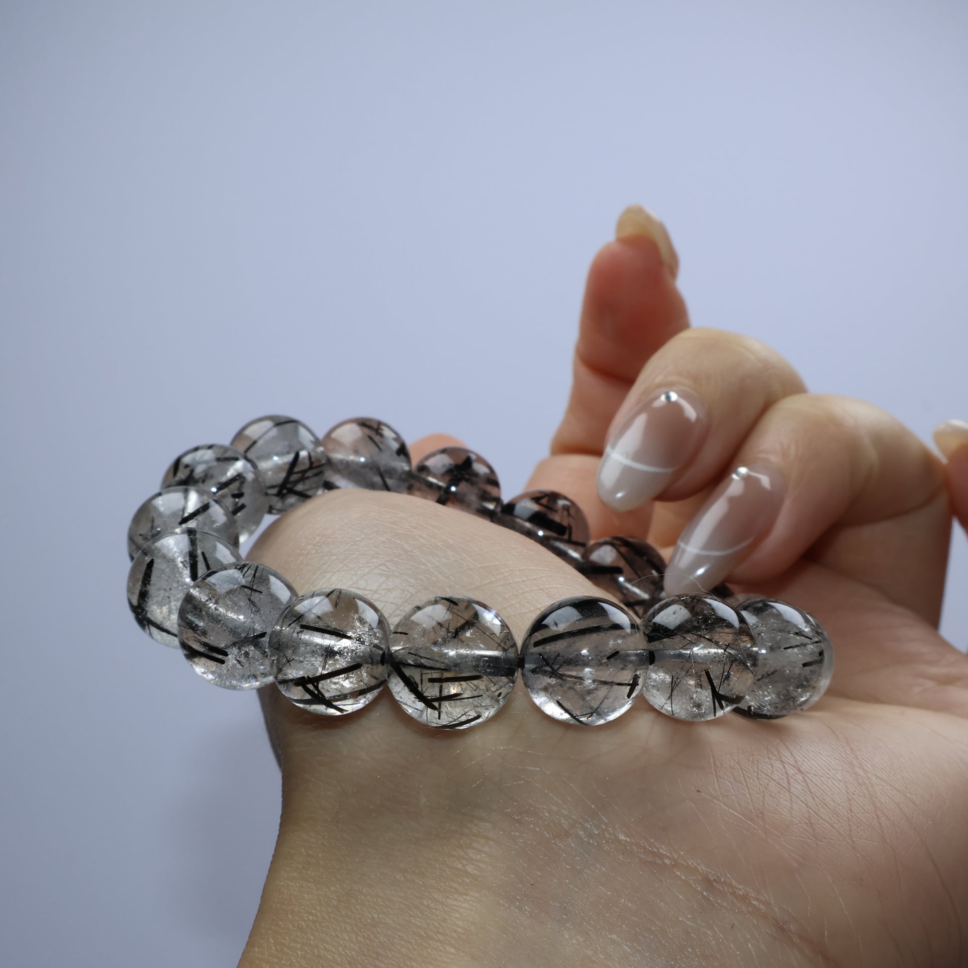 Curved wrist pose highlighting quartz transparency and sparse black threads