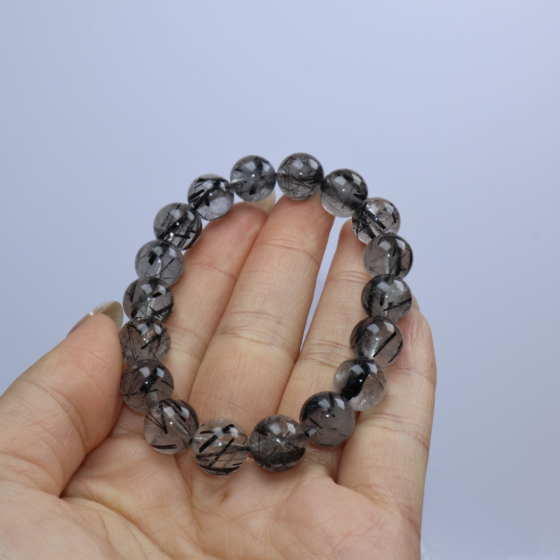 Handheld photo displaying bead clarity and dark rutile inclusions